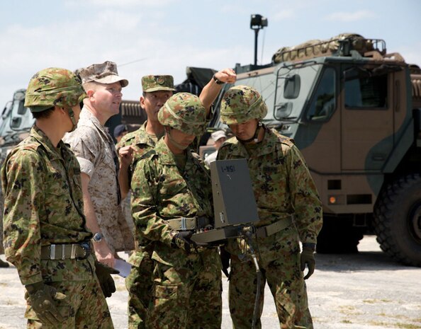 Japan Ground Self-Defense Force Col. Hidetoshi Fujita, center rear, explains the capabilities of an air-defense system to Marine Col. Scott F. Stebbins, center left, during a bilateral exhibition April 15 at Marine Corps Air Station Futenma. The demonstration was part of an overarching exhibition highlighting the air-defense capabilities of the 15th Anti-aircraft Artillery Regiment. Stebbins is the commanding officer of Marine Air Control Group 18, 1st Marine Aircraft Wing, III Marine Expeditionary Force. Fujita is the commander of the 15th AAR, 15th Brigade, Western Army, JGSDF. 