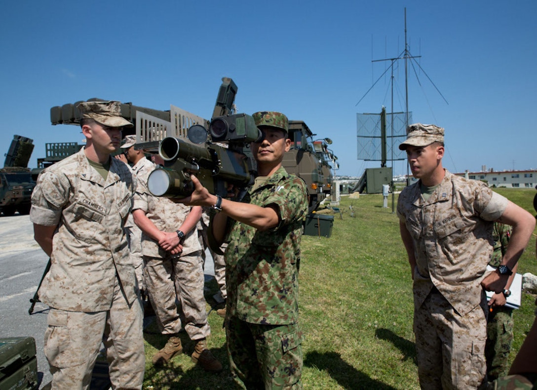 Japan Ground Self-Defense Force Col. Hidetoshi Fujita, center, holds a FIM-92 Stinger missile launcher alongside Marines with the Low Altitude Air Defense detachment, Marine Air Control Squadron 4, during a bilateral air-defense system exhibition April 15 at Marine Corps Air Station Futenma. The demonstration was part of an overarching exhibition highlighting the air-defense capabilities of the 15th Anti-aircraft Artillery Regiment. The systems included a Type 03 middle-range surface-to-air missile and Type 11 short-range SAM. Fujita is the commander of the 15th AAR, 15th Brigade, Western Army, JGSDF. The Marines are with MACS-4, Marine Air Control Group 18, 1st Marine Aircraft Wing, III Marine Expeditionary Force. 