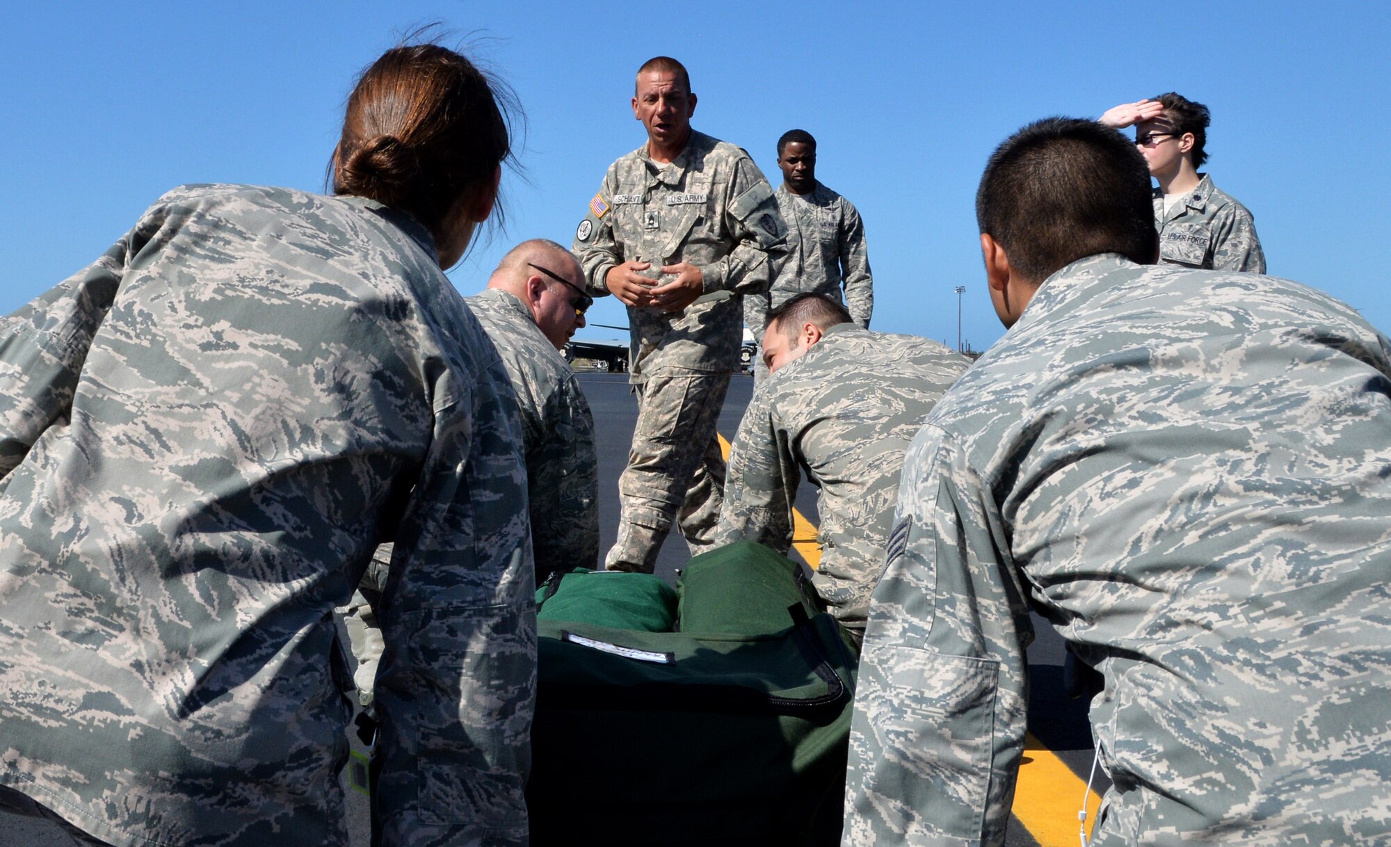 Army Sgt. 1st Class Michael Schantz (center), 3rd Battalion, 25th Aviation Regiment, instructs 15th Medical Group medics on proper patient litter lift techniques on the Hickam flightline during a joint training session April 17, 2014 at Joint Base Pearl Harbor-Hickam, Hawaii. The training taught the medics how to properly carry a litter and proper techniques for loading and unloading patients onto a bus, C-17 Globemaster III and a HH-60 Pave Hawk helicopter. (U.S. Air Force photo/Staff Sgt. Alexander Martinez)