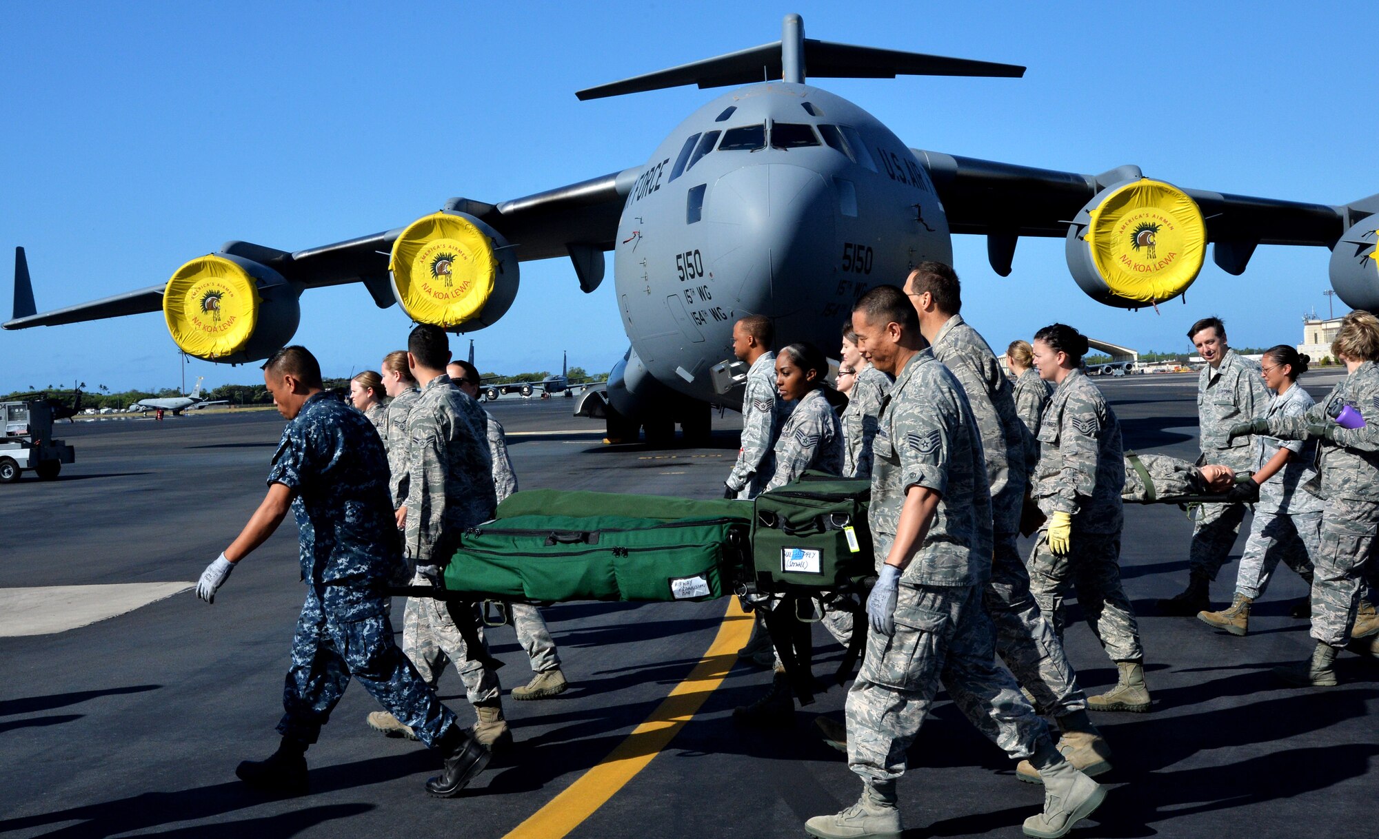 15th Medical Group Airmen and Navy medical corpsmen practice carrying a patient litter on the Hickam flightline during a joint training session April 17, 2014 at Joint Base Pearl Harbor-Hickam, Hawaii. The training taught the medics how to properly carry a litter and proper techniques for loading and unloading patients onto a bus, C-17 Globemaster III and a HH-60 Pave Hawk helicopter. (U.S. Air Force photo/Staff Sgt. Alexander Martinez)