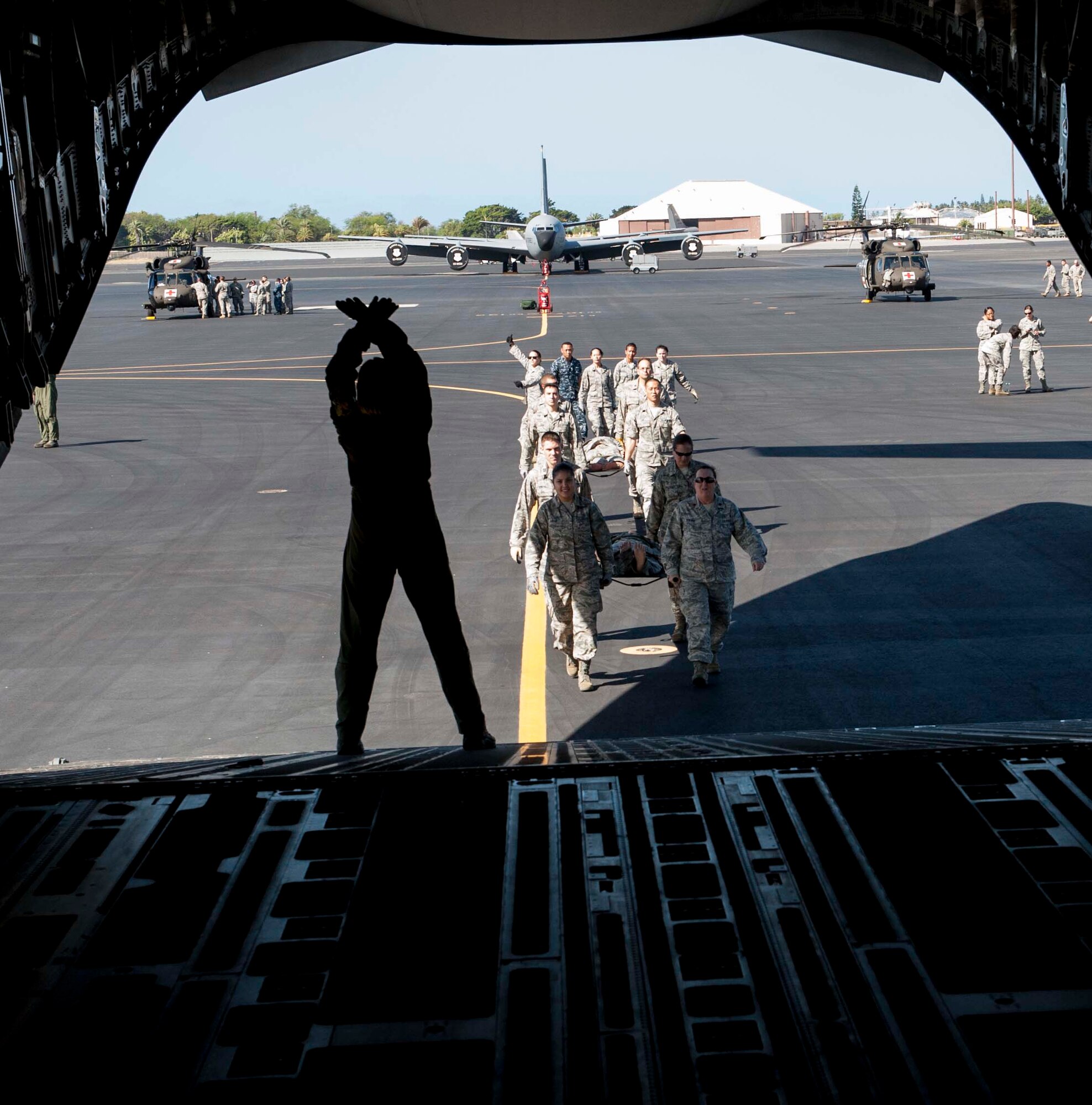 Maj. Donna Hornberger, 18th Aeromedical Evacuation Squadron, Detachment 1, marshals 15th Medical Group Airmen onto a C-17 Globemaster III during a patient movement training April 17, 2014 at Joint Base Pearl Harbor-Hickam, Hawaii. The Airmen partnered with the Army and Navy to receive training on how to load and unload patients onto a C-17, HH-60 Pave Hawk helicopter and a personnel transport bus. (U.S. Air Force photo/1st Lt. Andrea Dykes)