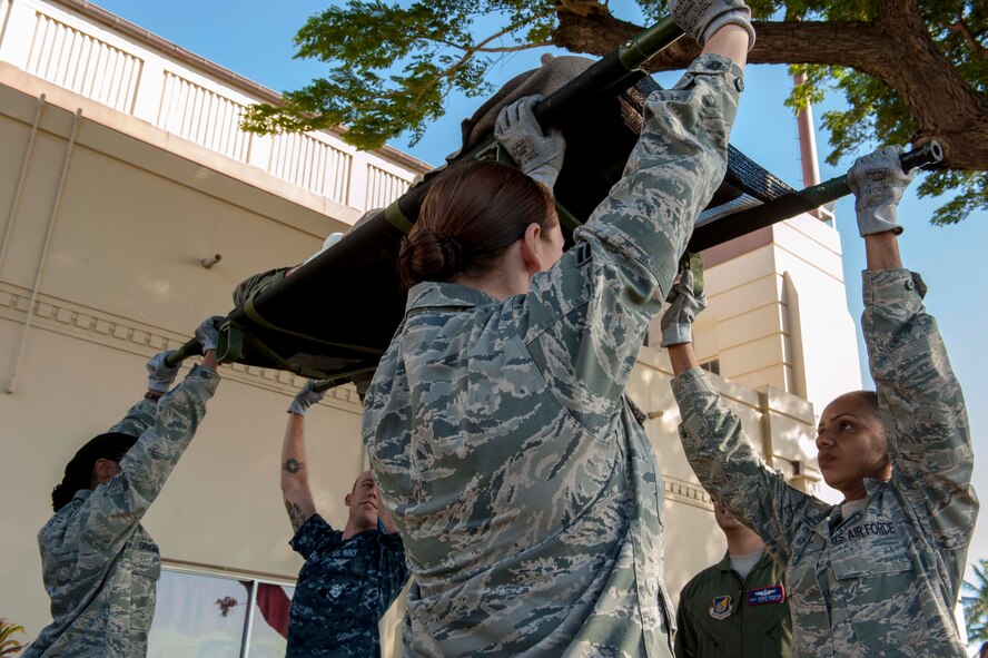 Members of the 15th Medical Group partnered with the 18th Aeromedical Evacuation Squadron, Detachment 1 and Army and Navy medics for patient transfer movement training April 17, 2014 at Joint Base Pearl Harbor-Hickam, Hawaii. The training helped the medics learn techniques behind loading and unloading patients on a HH-60 Pave Hawk helicopter, C-17 Globemaster III and a personnel transport bus. (U.S. Air Force photo/1st Lt. Andrea Dykes)