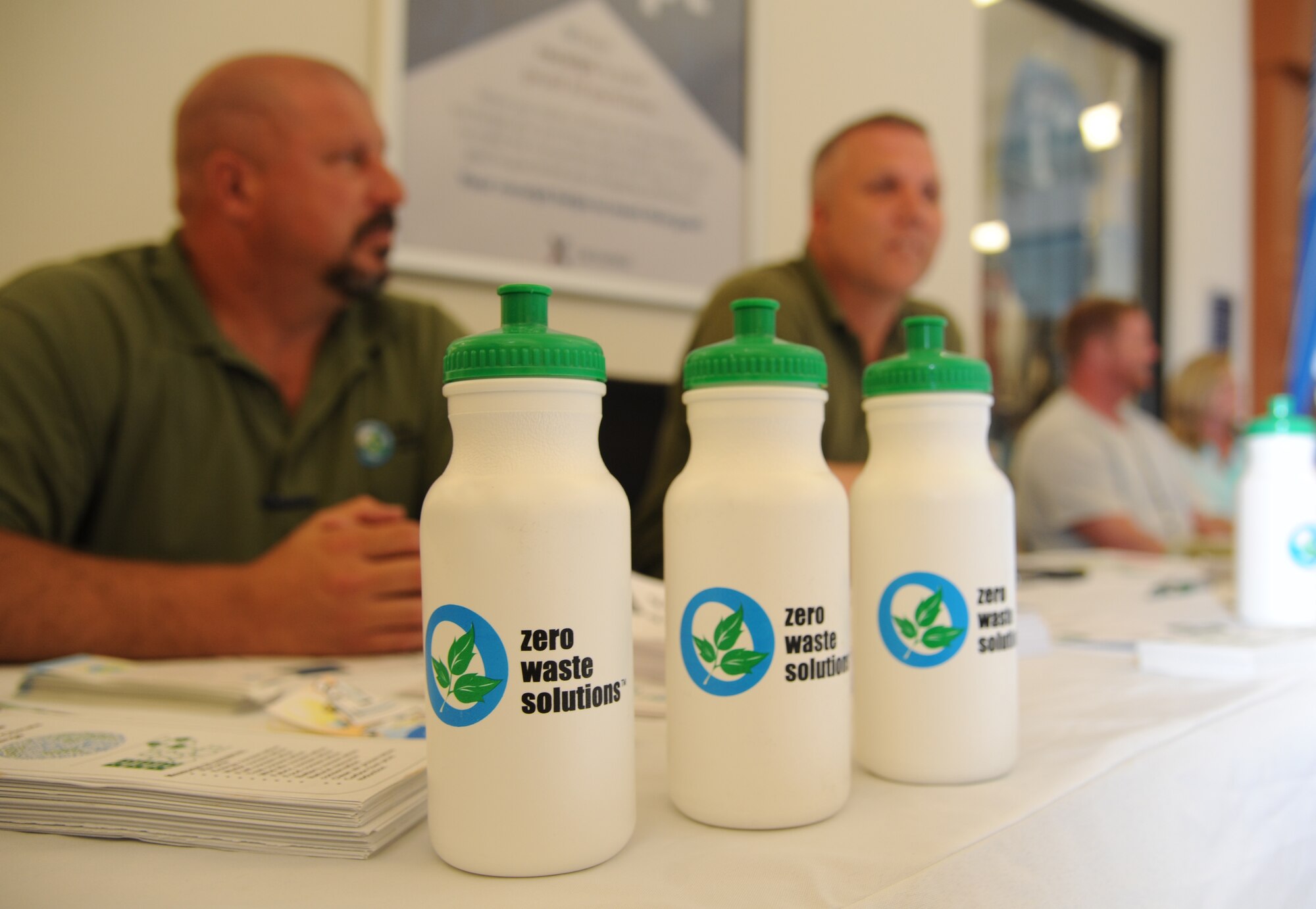 Duane Olsen and Douglas Smith, Zero Waste Solutions, provide informational recycling pamphlets, water bottles and office supplies made out of recycled materials to customers during their visit to the base exchange April 22, 2014, at Keesler Air Force Base, Miss.  Zero Waste Solutions and PAE/CEV set up booths with hand-outs and literature materials about recycling and environmental sustainability for Keesler personnel in recognition of Earth Day.  (U.S. Air Force photo by Kemberly Groue)