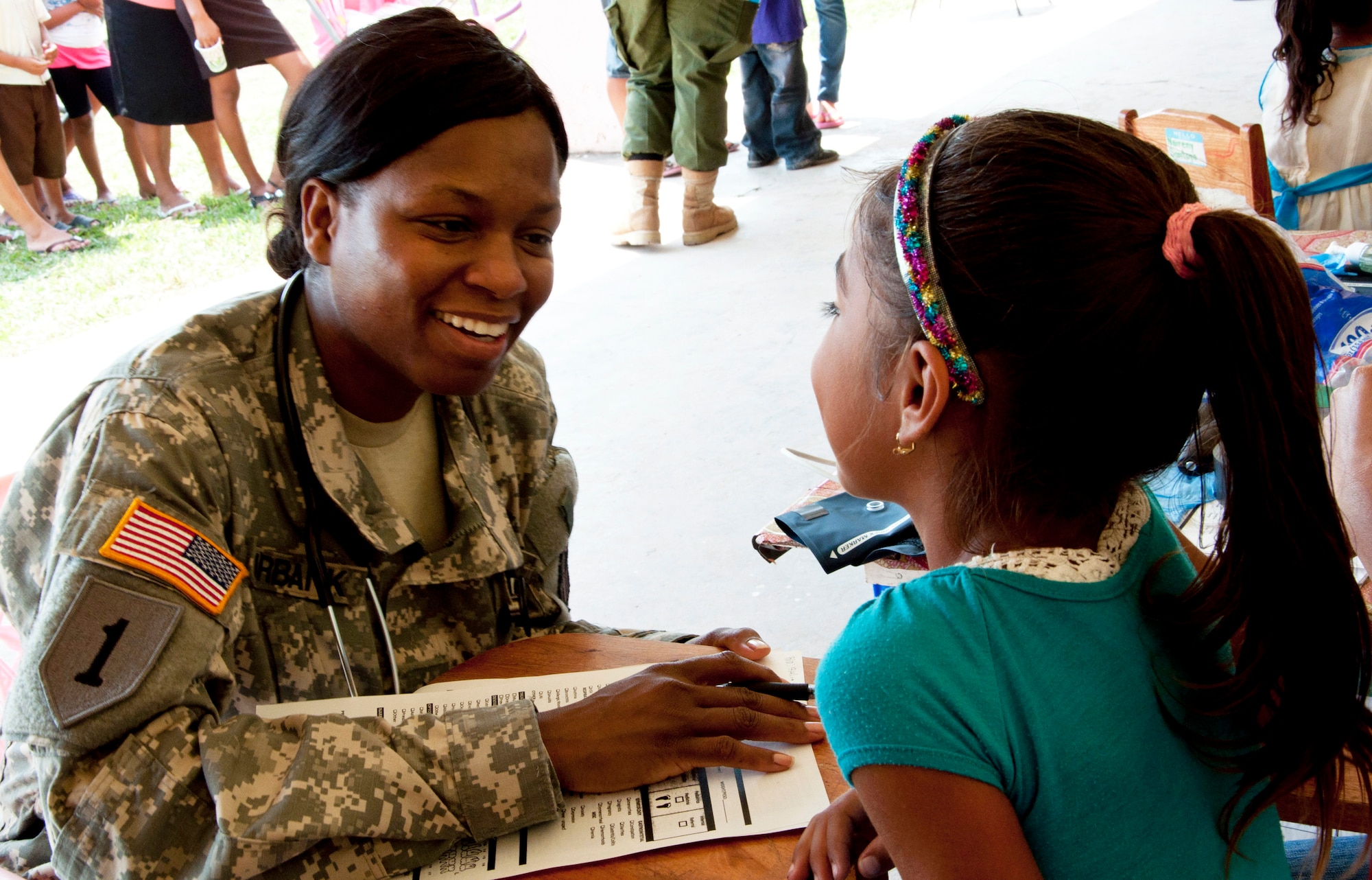 U.S. Army Sgt. Karen Burbank, medic, left, talks with a Belizean girl while checking her in for medical care April 7, 2014, at the Chunox Roman Catholic Pre-School in Chunox, Belize. Burbank, a Belize City native, is deployed from the 349th Combat Support Hospital, a Reserve unit in Los Angelas, Calif. The care was provided as part of a medical training exercise, or MEDRETE, that offers U.S. and Canadian military doctors and nurses the opportunity to train and interact with their Belizean counterparts. Free care will also be available 9 a.m. to 4 p.m. April 14-17 at the Libertad Methodist School. (U.S. Air Force photo by Tech. Sgt. Kali L. Gradishar/Released)