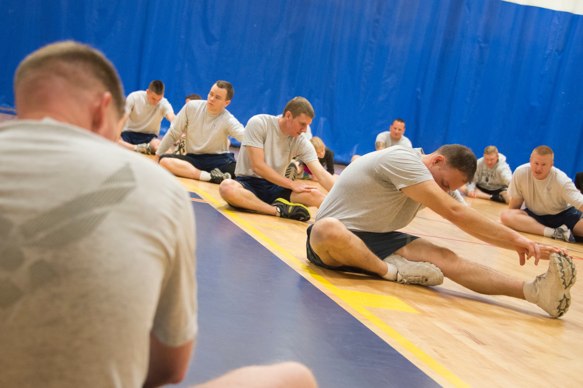 Members of the 85th Engineering Installation Squadron stretch at the close of the physical training session during the squadron’s family day April 18, 2014, at the Blake Fitness Center, Keesler Air Force Base, Miss.  The event also included a crawfish boil, an Easter egg hunt and a visit by the Easter Bunny.  (U.S. Air Force photo by Adam Bond)