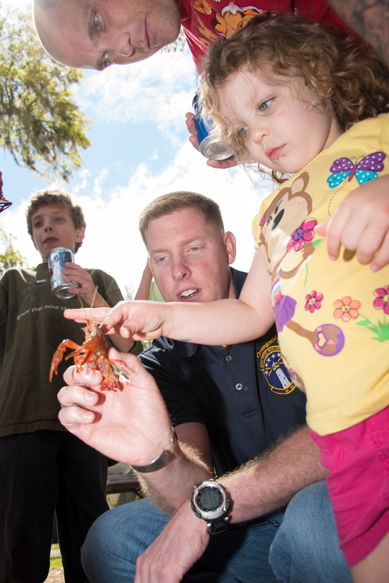 Lt. Col. James Coughlin, 85th Engineering Installation Squadron commander, demonstrates how to safely hold a crawfish to Staff Sgt. Michael Williams, 85th EIS, and his daughter, during the squadron’s family day crawfish boil April 18, 2014, at the marina, Keesler Air Force Base, Miss.  The event also included a physical training session, an Easter egg hunt and a visit by the Easter Bunny.  (U.S. Air Force photo by Adam Bond)