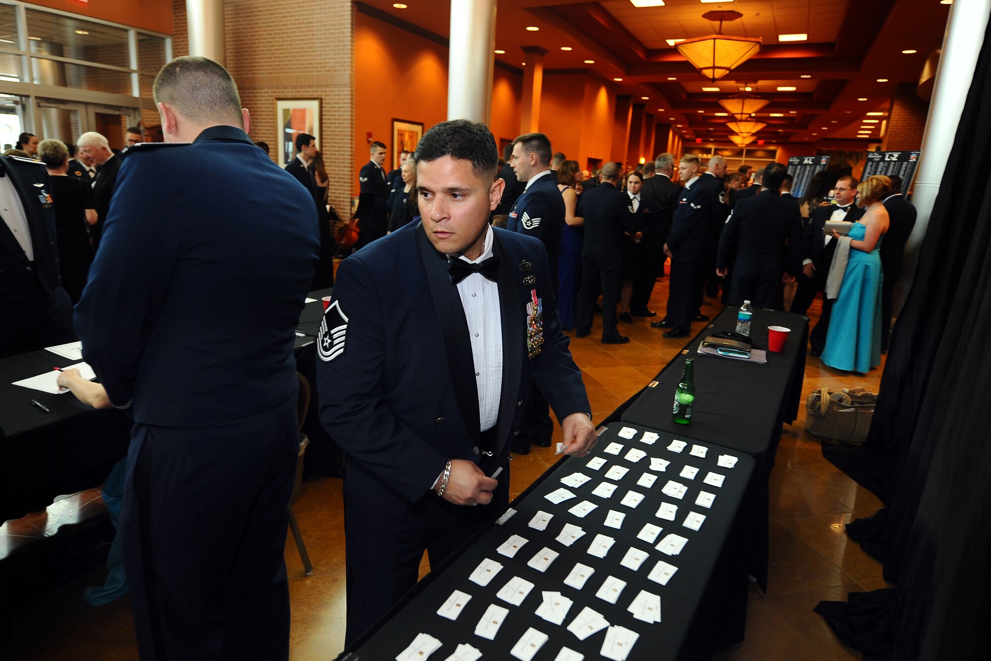 U.S. Air Force Master Sgt. Benito Colon, Jr., 55th Force Support Squadron, quickly gathers name tickets behind the check-in table as hundreds of people gather in the foyer of the Embassy Suites Hotel in LaVista, Neb, for the 36th annual 55th Wing Birthday Ball April 12. The Birthday Ball shattered its attendance record with more than 900 guests in attendence.  (U.S. Air Force photo by Josh Plueger/Released)