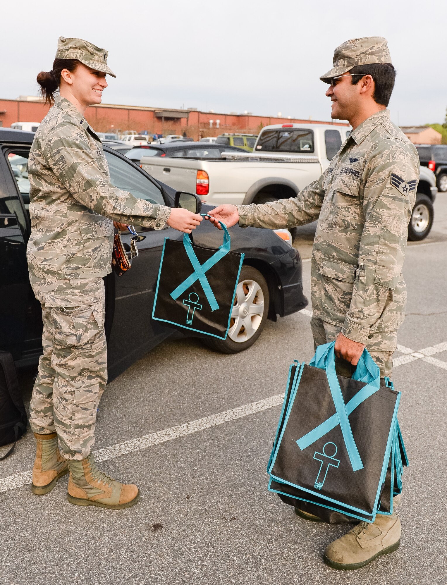 U.S. Air Force Senior Airman Joshua Guzman, 16th Airborne Command and Control Squadron, presents a decorative sexual assault awareness bag to 1st Lt. Sarah Kathe, 116th Medical Group, Georgia Air National Guard, during a parking lot blitz for the start of Sexual Assault Awareness Month at Robins Air Force Base, Ga., April 1, 2014. Airmen from the 116th and 461st Air Control wings volunteered to greet fellow Team JSTARS members as they came to work in the morning to spread the word about Sexual Assault Awareness Month. (U.S. Air National Guard photo by Master Sgt. Roger Parsons/Released)