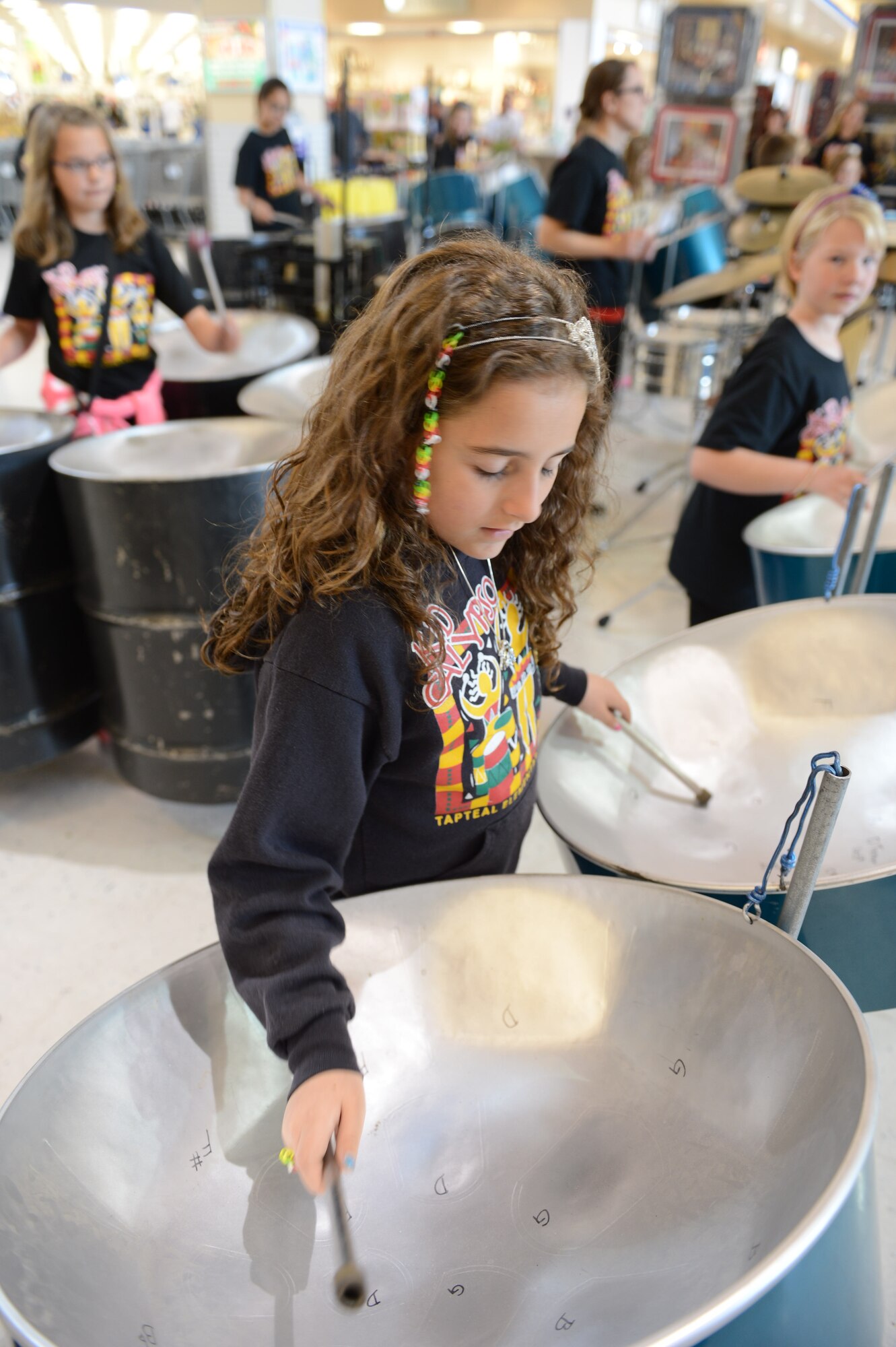 A child from the group "Kid Calypso," a steel drum band from Tapteal Elementary School, West Richland, Wash., performs on a steel drum for Team McChord Airmen and their families at the McCord Main Exchange, April 18, 2014, at Joint Base Lewis-McChord, Wash. The children visited the McChord Field museum and air park prior to this 45-minute performance. (U.S. Air Force photo/A1C Jacob Jimenez)