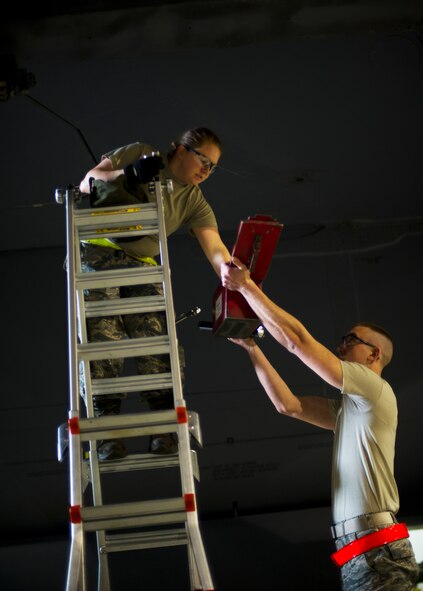 Senior Airman Adam Schaetzl assists SrA Kasey Castor, 5th Aircraft Maintenance Squadron weapons load crew members, with loading a Joint Direct Attack Missile trainer on a B-52H Stratofortress during a weapons-loading competition at Minot Air Force Base, N.D., April 17, 2014. Each load crew consists of four Airmen who are evaluated every month on how well they load various types of weapons. (U.S. Air Force photo/Senior Airman Brittany Y. Auld)