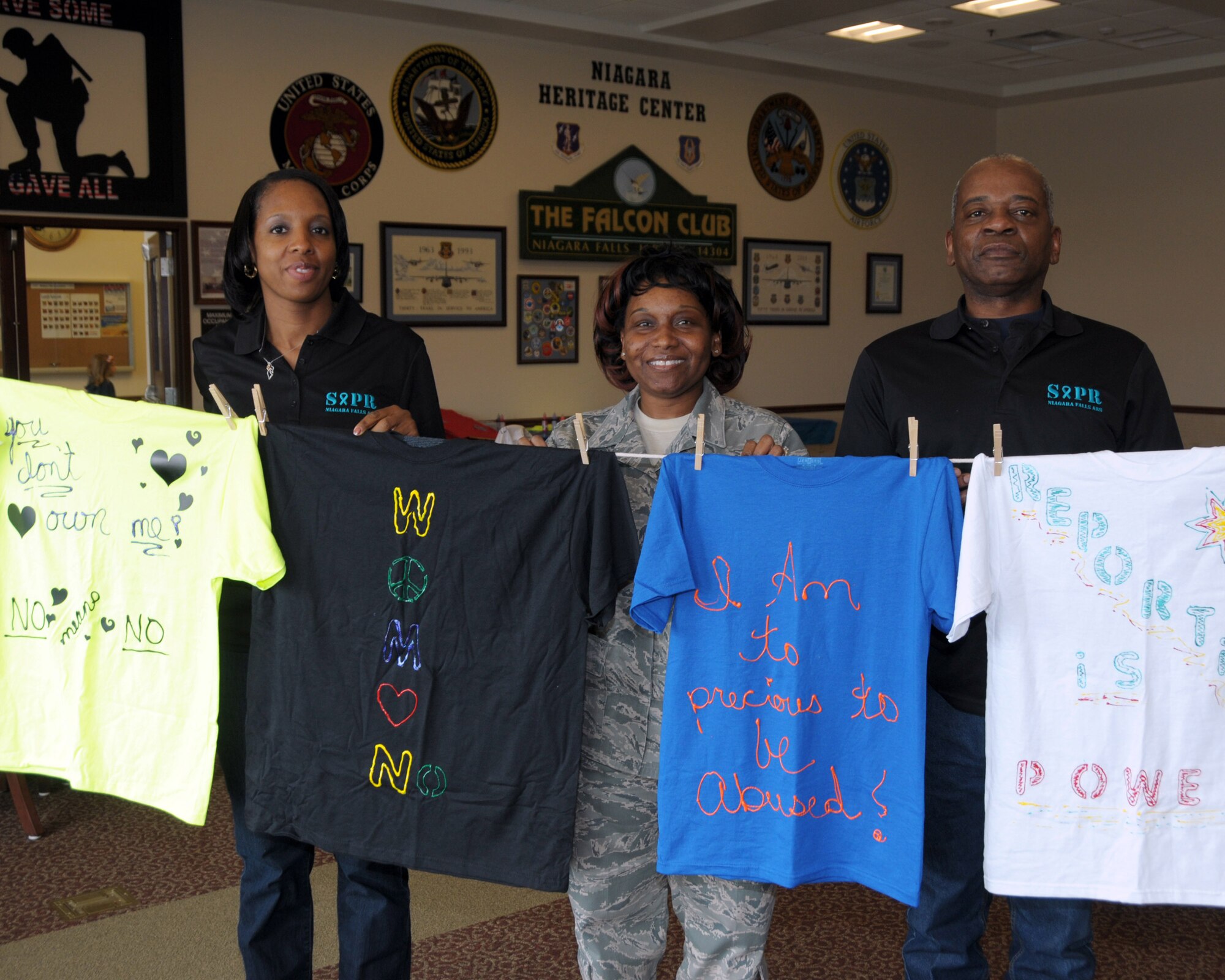(L to R) Ms. Nikki Slaughter Sexual Assault Response Coordinator, 914th Airlift Wing, MSgt. Francenia Reed-McKnight, Administrative Specialist, 914th Aeromedical Evacuation Squadron, Mr. Allan Davidson, Weapons Safety Manager, 914th Airlift Wing show off some of the creative messages on t-shirts for this year's Clothesline Project to help End Sexual Assault & Domestic Violence at the Niagara Falls Air Reserve Station, NY on April, 18, 2014.  (U.S. Air Force photo by Peter Borys)