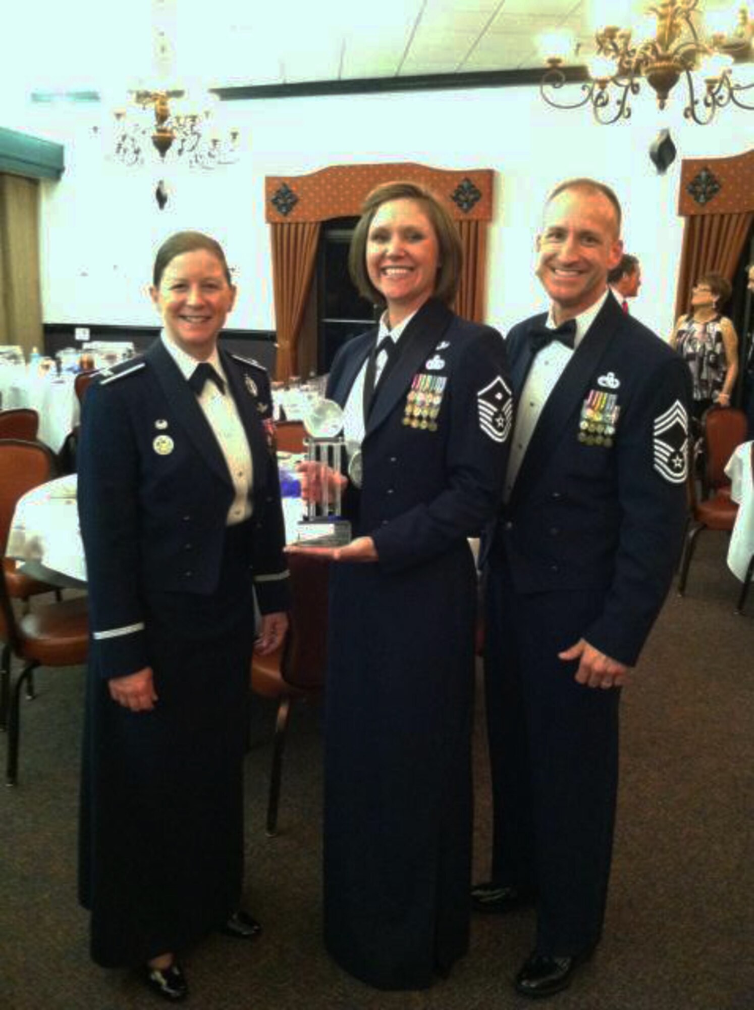 Master Sgt. Rebecca McNelley, 790th Missile Security Forces Squadron, holds up the 2013 Air Force Global Strike Command’s First Sergeant of the Year award April 10 after a ceremony at Barksdale Air Force Base, La., while Col. Tracey Hayes, 90th Missile Wing commander, and Chief Master Sgt. Samuel S. Couch, incoming 90th MW command chief, stand by her. 