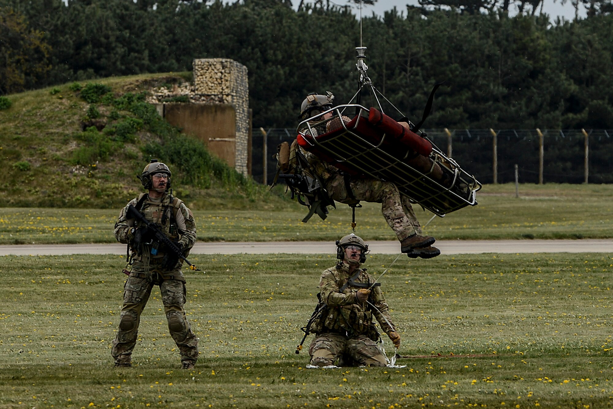 Senior Master Sgt. Brandon Casteel, 56th Rescue Squadron operations superintendent, is hoisted into an HH-60G Pave Hawk with a litter carrying the mock crash victim away from the scene during a combat search and rescue exercise at Royal Air Force Lakenheath, England, April 17, 2014. The rescue mission scenario included pararescue and security forces teams recovering a victim injured by an improvised explosive device. (U.S. Air Force photo by Airman 1st Class Trevor T. McBride/Released)