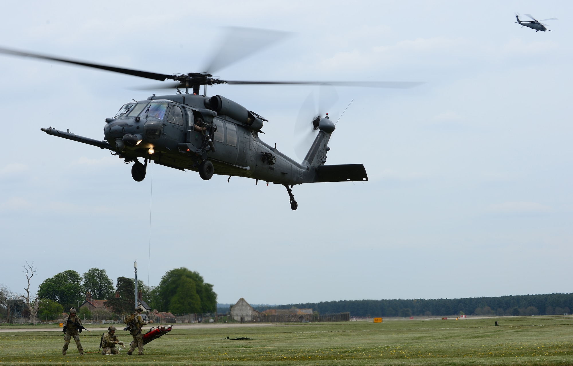 A 56th Rescue Squadron pararescue team straps in the mock crash scene victim before hoisting up into an HH-60G Pave Hawk during a combat search and rescue exercise at Royal Air Force Lakenheath, England, April 17, 2014. The rescue mission scenario included pararescue and security forces teams recovering a victim injured by an improvised explosive device. (U.S. Air Force photo by Staff Sgt. Emerson Nuñez/Released)