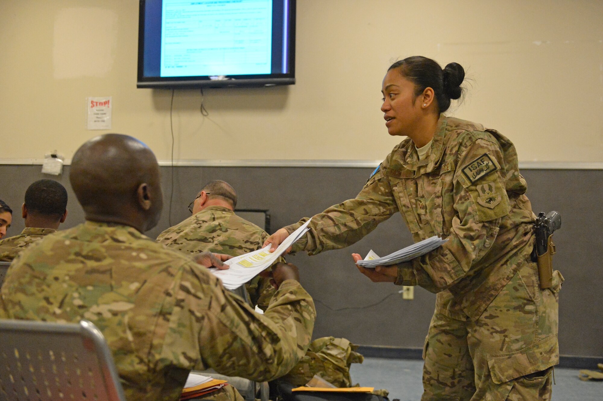 U.S. Air Force Senior Airman Desirae Faasavalu passes out paperwork during the in-processing briefing for Airmen arriving at Bagram Airfield, Afghanistan, April 17, 2014. Faasavalu is assigned to the 455th PERSCO (Personnel Support for Contingency Operations) team, and is responsible for in-processing of Airmen arriving at Bagram.(U.S. Air Force photo by Senior Master Sgt. Gary J. Rihn/Released)  