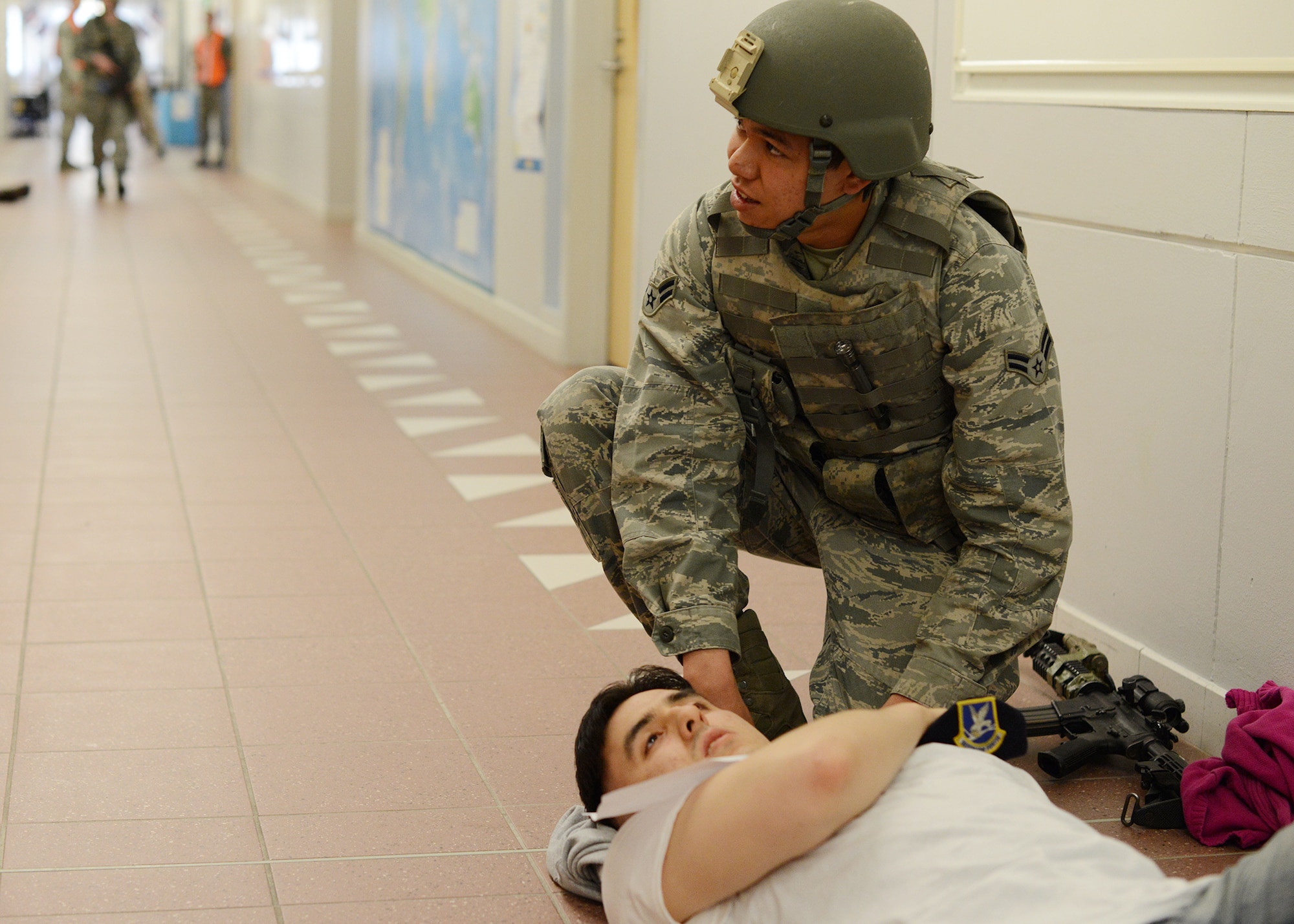 Airman 1st Class Jenson Kaopuiki, 31st Security Forces Squadron defender, applies self-aid and buddy care to a simulated victim during an active shooter training exercise at the Aviano Air Base Elementary School, April 19, 2014. The SFS Airmen culminated their week-long active shooter training with a hands-on exercise that tested their abilities to respond in a stressful situation. The training was made as real as possible with simulated rounds and victims spread throughout the school for the defenders to locate and treat. (U.S. Air Force photo/Tech. Sgt. Eric Donner)