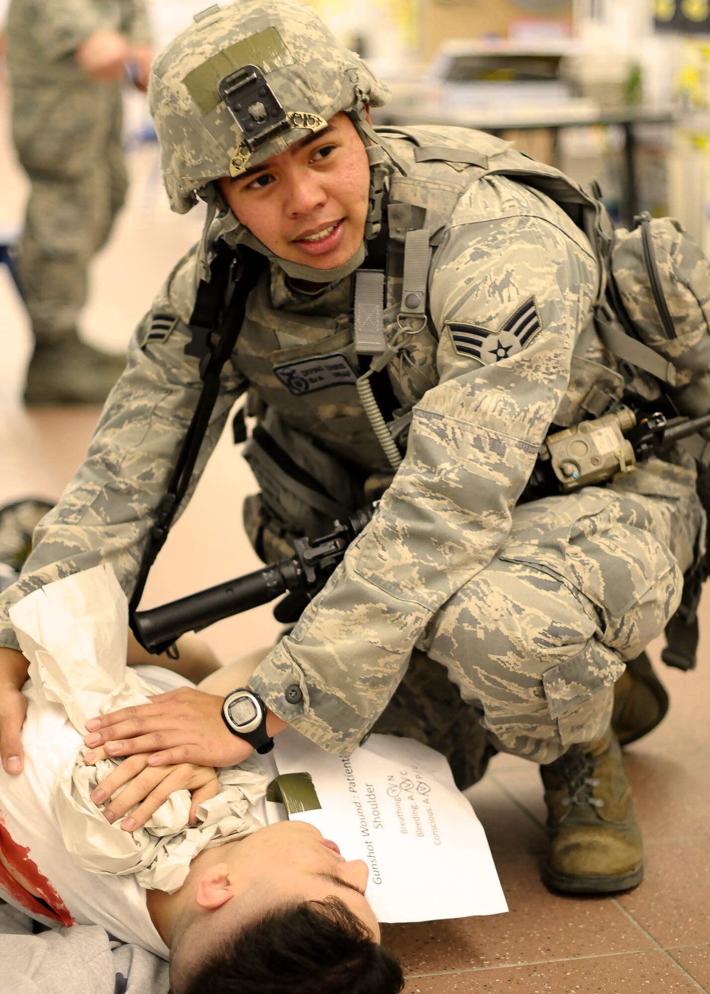 Senior Airman Chris Divino, 31st Security Forces Squadron defender, applies self-aid and buddy care to a simulated victim during an active shooter training exercise at the Aviano Air Base Elementary School, April 19, 2014. The SFS Airmen culminated their week-long active shooter training with a hands-on exercise that tested their abilities to respond in a stressful situation. (U.S. Air Force photo/Tech. Sgt. Eric Donner)