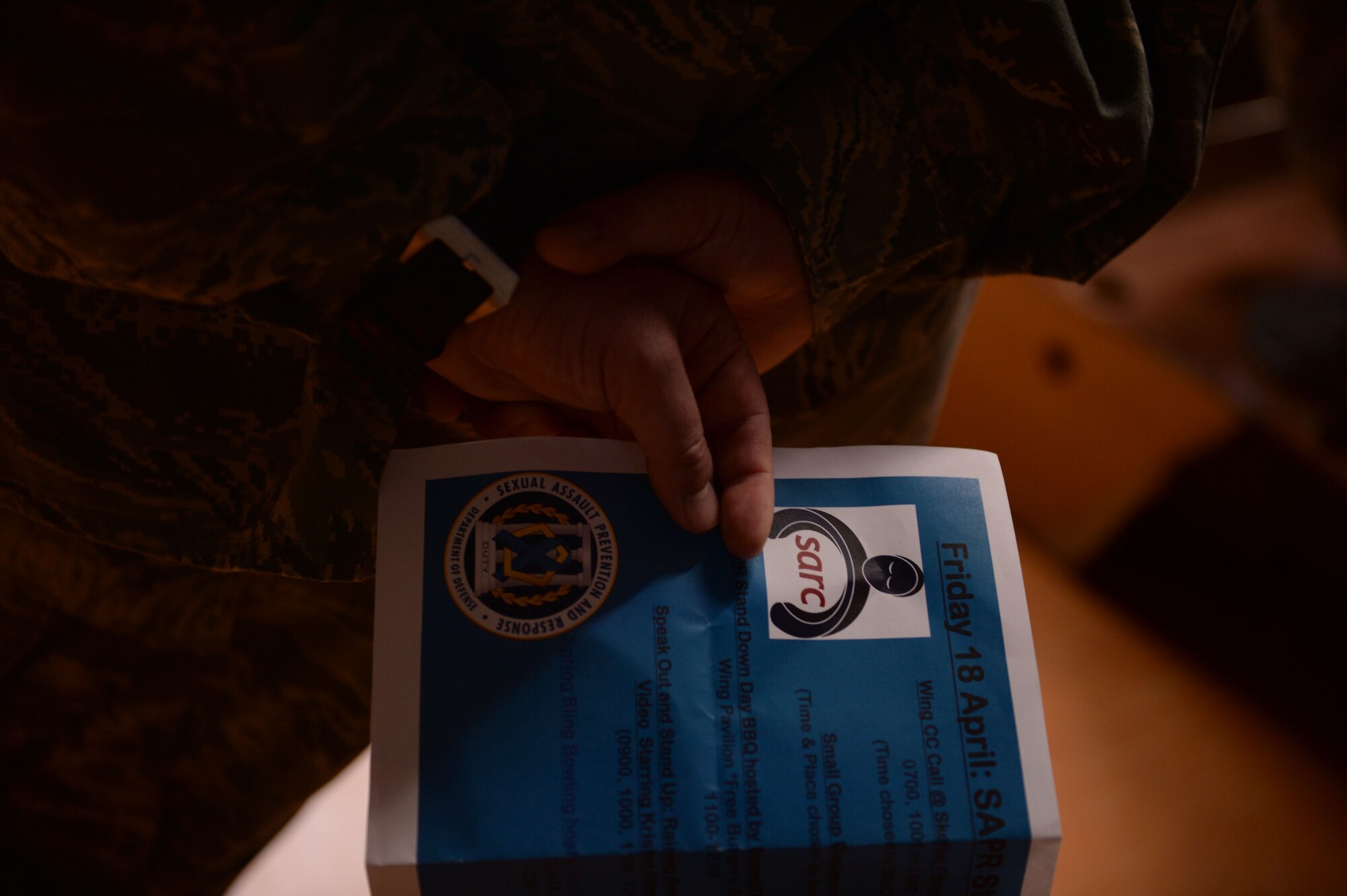 A participant in a Sexual Assault Prevention and Response down day all call holds a flyer behind his back at the Skelton Memorial Fitness Center on Spangdahlem Air Base, Germany, April 18, 2014. The all call focused on identifying perpetrators of sexual assault. (U.S. Air Force photo by Senior Airman Alexis Siekert/Released)