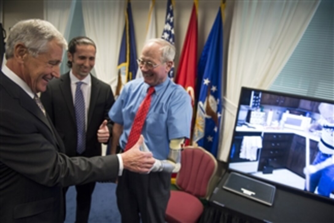 Defense Secretary Chuck Hagel, left, thumb wrestles Frederick Downs Jr., a fellow Vietnam War veteran Hagel has known for more than 30 years, during a prosthetics presentation at the Pentagon, April 22, 2014. The Defense Advanced Research Projects Agency, or DARPA, also showcased the Atlas robot, long-range anti-ship missile and persistent close air support.