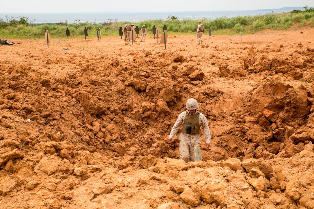 Lance Cpl. Nickolaus D. Lopez examines a crater made by the explosion of a 40-pound ammonium nitrate crater charge April 15 at Camp Schwab during a four-day basic demolition course. The enormous power generated by the explosive did not allow for a safe viewing of the detonation by the Marines. Lopez is a combat engineer with Marine Wing Support Squadron 172, Marine Aircraft Group 36, 1st Marine Aircraft Wing, III Marine Expeditionary Force.