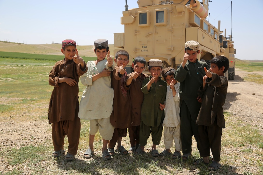 Afghan children gather and show thumbs up for a photo as Marines with Weapons Company, 1st Battalion, 7th Marine Regiment, pass through a village during a mission in Helmand province, Afghanistan, April 17. The company's two-day mission was to disrupt lethal enemy aid and to search three compounds of interest in an area suspected of Taliban influence. The compounds were suspected to contain a homemade-explosive lab, a cache for narcotics and be home to local Taliban leadership.