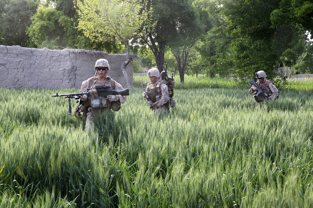 Lance Cpl. Shawn Madruga, left, machine gunner, Weapons Company, 1st Battalion, 7th Marine Regiment, and a native of Tuolumne, Calif., leads Marines out of a field during a mission in Helmand province, Afghanistan, April 17. The company's two-day mission was to disrupt lethal enemy aid and to search three compounds of interest in an area suspected of Taliban influence. The compounds were suspected to contain a homemade-explosive lab, a cache for narcotics and be home to local Taliban leadership.