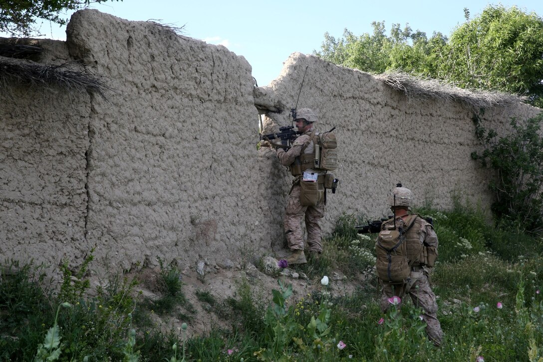 Captain Scott Stewart, commanding officer, Weapons Company, 1st Battalion, 7th Marine Regiment, and a native of El Cajon, Calif., scans for suspicious activity through a hole in a mud wall during a mission in Helmand province, Afghanistan, April 17. The company's two-day mission was to disrupt lethal enemy aid and to search three compounds of interest in an area suspected of Taliban influence. The compounds were suspected to contain a homemade-explosive lab, a cache for narcotics and be home to local Taliban leadership.