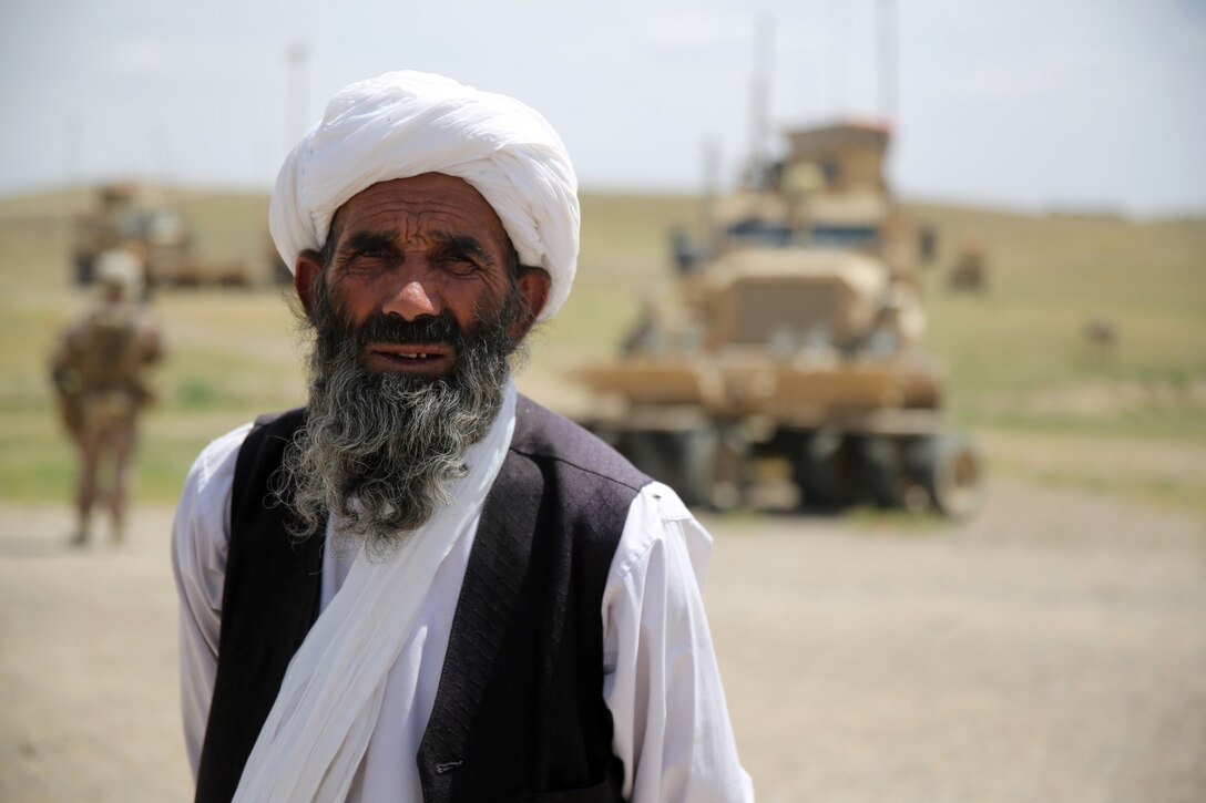 A local Afghan elder poses for a photo as Marines with Weapons Company, 1st Battalion, 7th Marine Regiment, pass through a village during a mission in Helmand province, Afghanistan, April 17. The company's two-day mission was to disrupt lethal enemy aid and to search three compounds of interest in an area suspected of Taliban influence. The compounds were suspected to contain a homemade-explosive lab, a cache for narcotics and be home to local Taliban leadership.