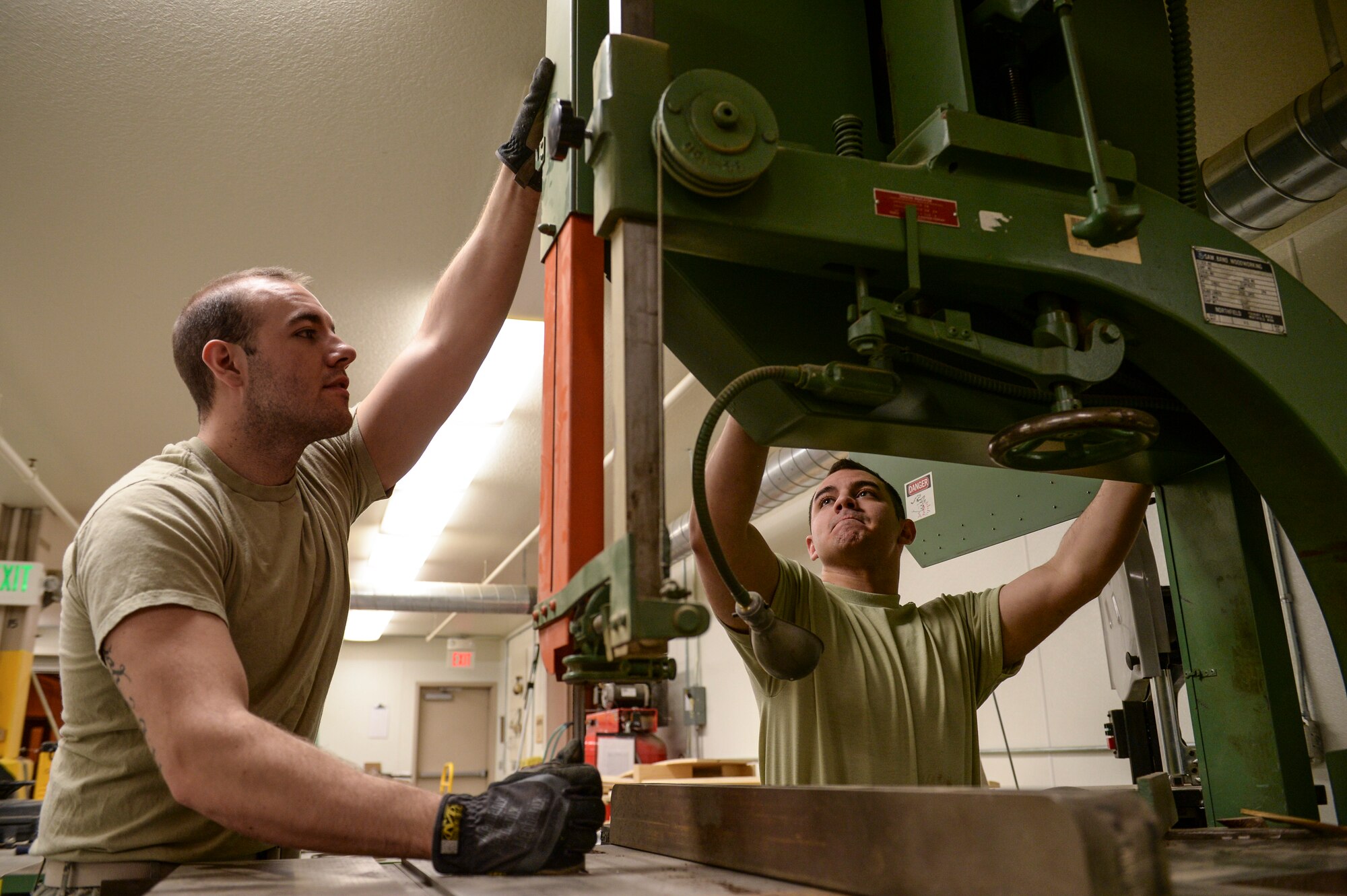 U.S. Air Force Airman 1st Class Paul Bissett and Senior Airman Raymond Ramirez, 354th Logistics Readiness Squadron traffic management specialists, check a band saw for tension and alignment at the 354th LRS warehouse April 17¬, 2014, Eielson Air Force Base, Alaska. Bissett and Ramirez specialize in creating custom-fitted woodwork for protecting and transporting military assets. (U.S. Air Force photo by Senior Airman Peter Reft/Released)