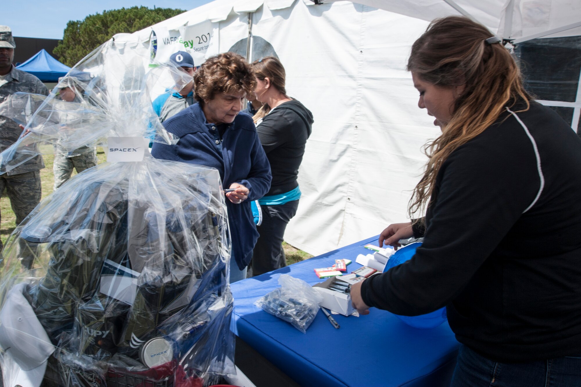 Katy Smith, SpaceX environmental health and safety intern, gives out SpaceX souvenirs during the 14th Annual Earth Day celebration April 23, 2014, Vandenberg Air Force Base, Calif. The 30th Civil Engineer Squadron hosted the event that showcased Vandenberg and the surrounding communities’ efforts to be “green.” (U.S. Air Force photo/ Airman 1st Class Yvonne Morales)