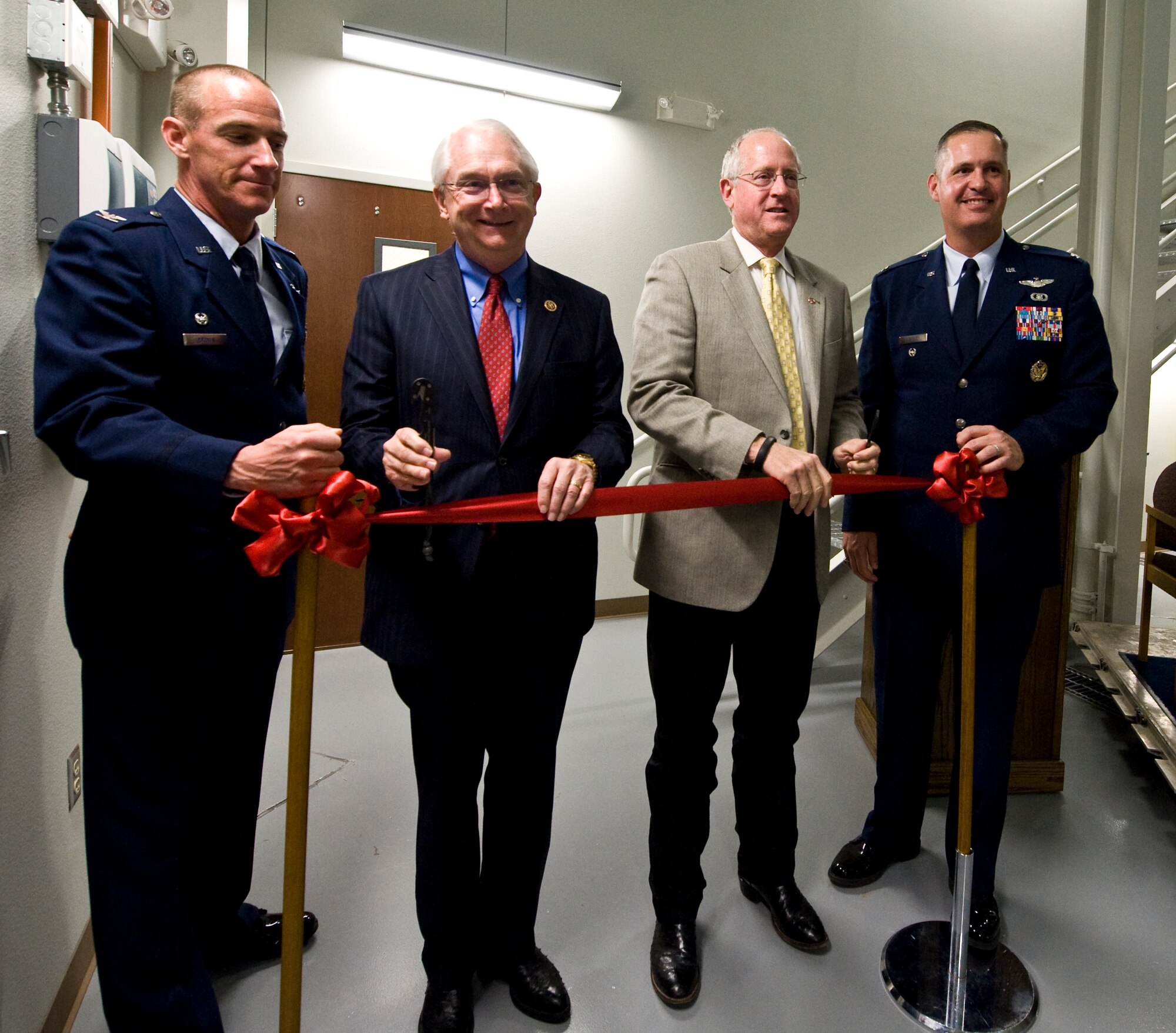 U.S. Air Force Col. Jeffrey Brown, left, U.S. Reps. Randy Neugebauer and Mike Conaway, center, and Col. Steven Beasley, cut the ribbon to mark the activation of the new C-130J Super Hercules simulator April 22, 2014, at Dyess Air Force Base, Texas. The new simulator will be used to build and maintain operator proficiency in the aircraft throughout multiple mission sets, including those not readily available during local flying missions. (U.S. Air Force photo by Staff Sgt. Richard Ebensberger/Released)