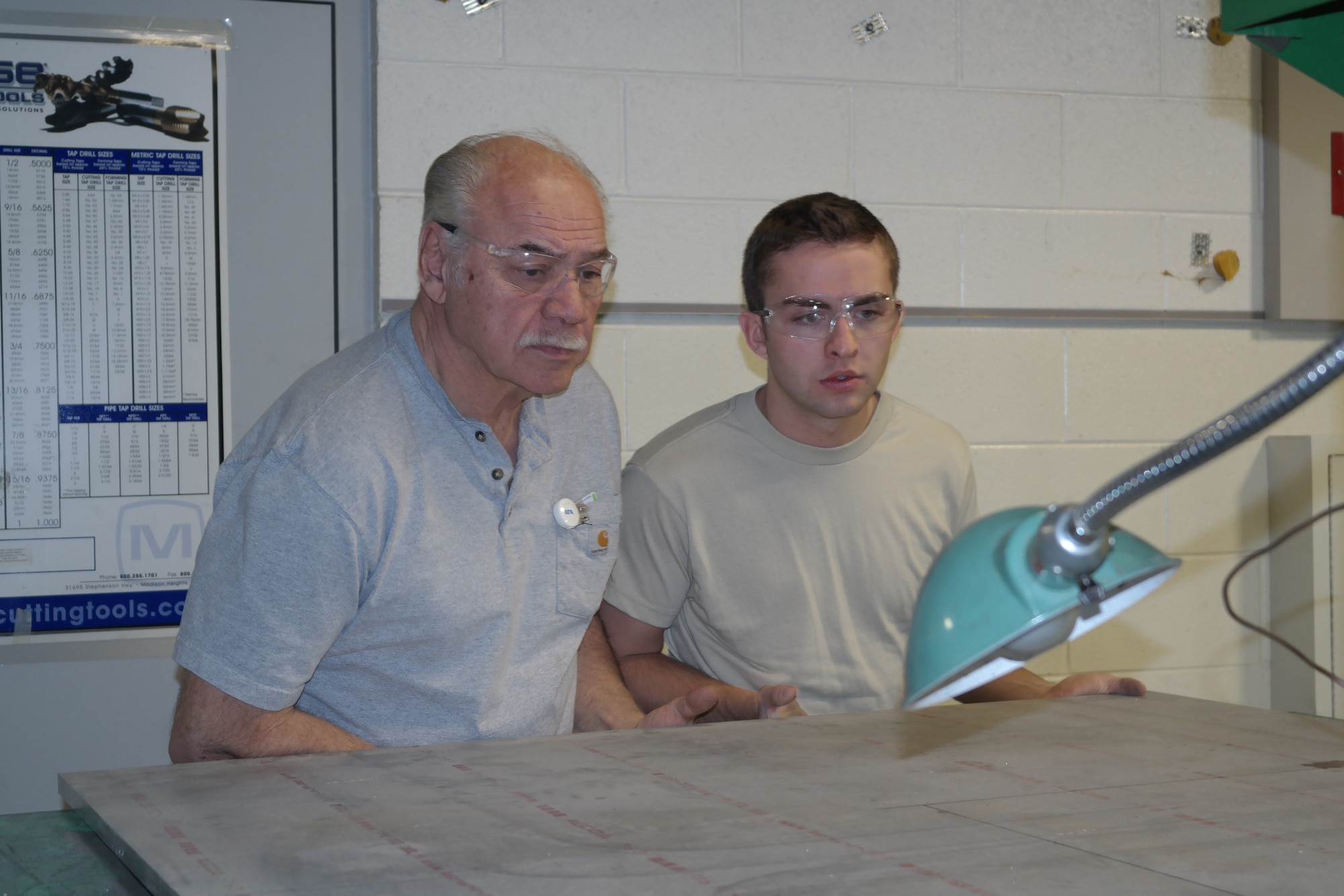 Renny Strackany, left, a machine technician in the Space Systems Research Center, helps Cadet 1st Class Garret Wilson cut a metal sheet to specifications for the Falcon Satellite project. (Sam Lee/U.S. Air Force photo)