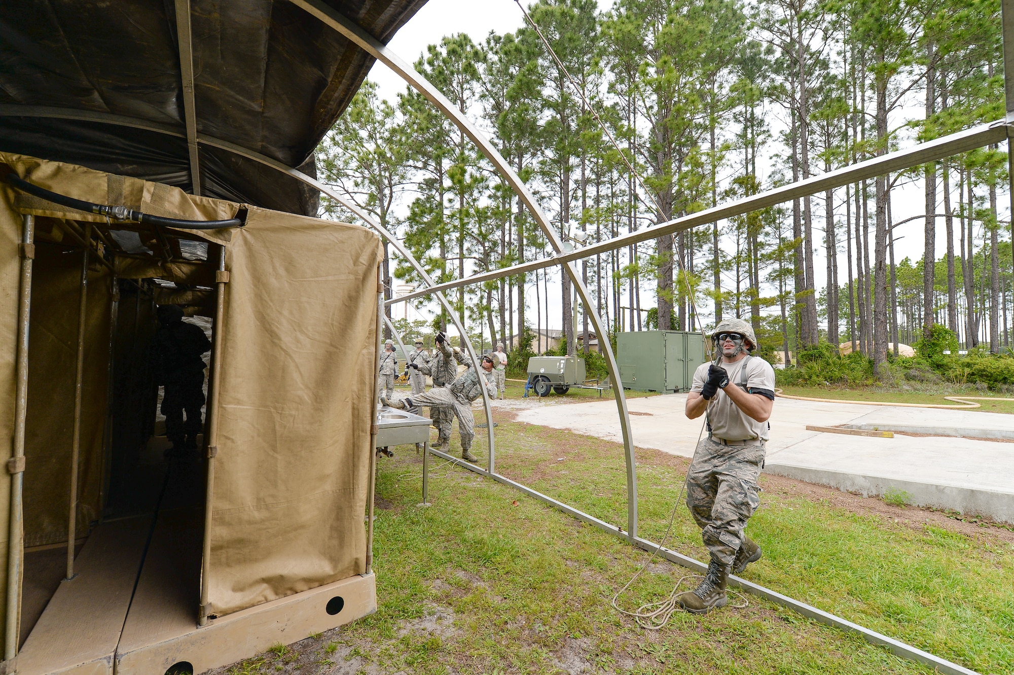 U.S. Air Force Staff Sgt. Jerry Vincent, water and fuel systems maintenance specialist with the 116th Civil Engineering Squadron (CES), Georgia Air National Guard (ANG), Robins Air Force Base, Ga., pulls the outer cover over a tent while erecting a shelter at Silver Flag training at Tyndall Air Force Base, Fla., April 17, 2014. During the weeklong course, Guardsmen from the 116th CES along with 219 Airmen from multiple U.S. Air Force active duty, Reserve and ANG units trained on building and maintaining bare-base operations at a simulated forward-deployed location. In addition, they honed their combat and survival skills, repaired simulated bomb-damaged runways, practiced EOD scenarios, set up base facilities and established various critical base operating support capabilities. Thirty-four Airmen from the 116th CES attended the exercise that consisted of extensive classroom and hands-on training culminating in an evaluation of learned skills on the last day of class. (U.S. Air National Guard photo by Master Sgt. Roger Parsons/Released)