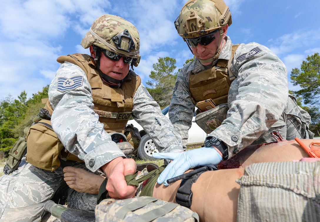 U.S. Air Force Tech. Sgt. Barry Duffield, left, an explosive ordnance disposal (EOD) technician with the 116th Civil Engineering Squadron (CES), Georgia Air National Guard (ANG), Robins Air Force Base, Ga., and Tech. Sgt. Dustin Turner, an EOD technician with the 123rd Airlift Wing, Kentucky ANG, Louisville, Ky., attempt to stop bleeding from the leg of a Multiple Amputation Trauma Trainer during Silver Flag training at Tyndall Air Force Base, Fla., April 17, 2014. During the weeklong course, Guardsmen from the 116th CES along with 219 Airmen from multiple U.S. Air Force active duty, Reserve and Air National Guard units trained on building and maintaining bare-base operations at a simulated forward-deployed location. In addition, they honed their combat and survival skills, repaired simulated bomb-damaged runways, practiced EOD scenarios, set up base facilities and established various critical base operating support capabilities. Thirty-four Airmen from the 116th CES attended the exercise that consisted of extensive classroom and hands-on training culminating in an evaluation of learned skills on the last day of class. (U.S. Air National Guard photo by Master Sgt. Roger Parsons/Released)