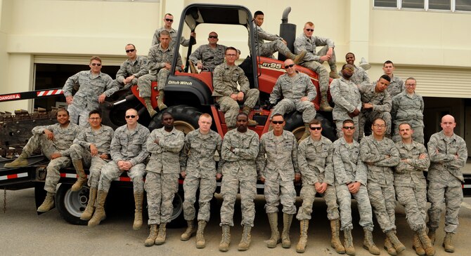 "Cable Dawgs" from the 18th Communications Squadron pose for a group photo atop a trencher on Kadena Air Base, Japan, April 16, 2014. Installing more than 28,000 feet of direct fiber cables underground into the airfields localizers, glide scopes and its VORTAC, the fiber optics will replace the 20-to 30-year-old copper circuits the airfield is currently utilizing and upgrade its infrastructure to allow the airfield to receive remote maintenance and system updates from the regional maintenance center at Yokota Air Base, Japan. (U.S. Air Force photo by Airman 1st Class Keith James)