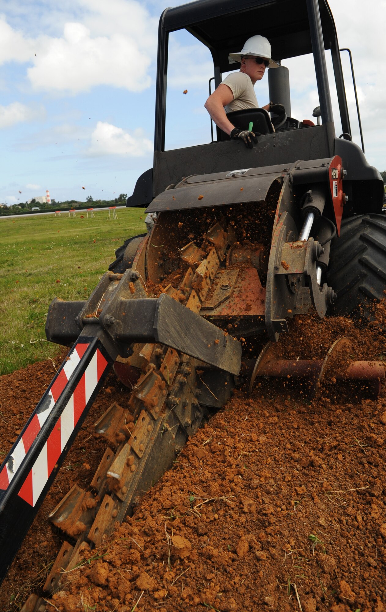 U.S. Air Force Airman 1st Class Jake Shroader, 18th Communications Squadron cable and antenna systems technician, uses a trencher to dig a hole for fiber optic cable during a fiber optic installation to the airfield on Kadena Air Base, Japan, April 14, 2014. A trencher is a piece of construction equipment used to dig trenches, especially for laying pipes or cables. (U.S. Air Force photo by Airman 1st Class Keith James)