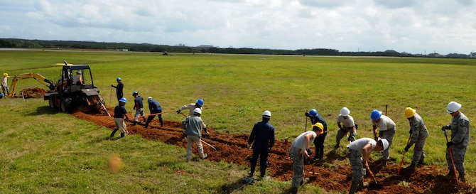 "Cable Dawgs" from the 18th Communications Squadron use a small excavator and shovels to fill the hole made by a trencher during fiber optic cable installation to the airfield on Kadena Air Base, Japan, April 14, 2014. Installing more than 28,000 feet of direct fiber cables underground into the airfield's localizers, glide scopes and its VORTAC, the fiber optics will replace the 20-to 30-year-old copper circuits the airfield is currently utilizing and upgrade its infrastructure to allow the airfield to receive remote maintenance and system updates from the regional maintenance center at Yokota Air Base, Japan. (U.S. Air Force photo by Airman 1st Class Keith James)