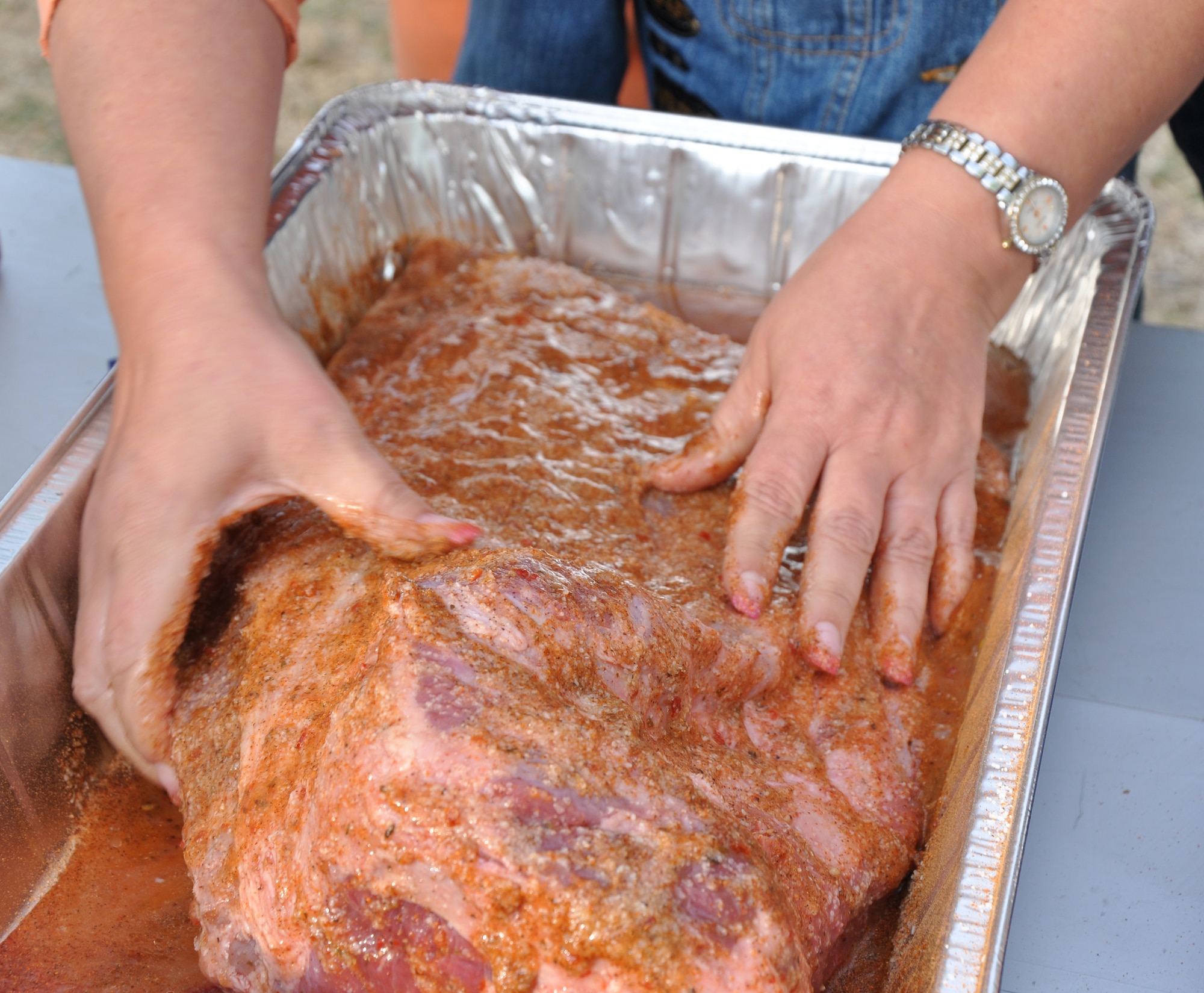 GOODFELLOW AIR FORCE BASE, Texas – A brisket class participant massages salt, salad dressing and seasoning into a brisket at the Goodfellow Recreation Camp here April 19. After the students seasoned the brisket and smoked it for an hour, the students soaked the meat in apple juice. (U.S. Air Force photo/ Senior Airman Joshua Edwards)