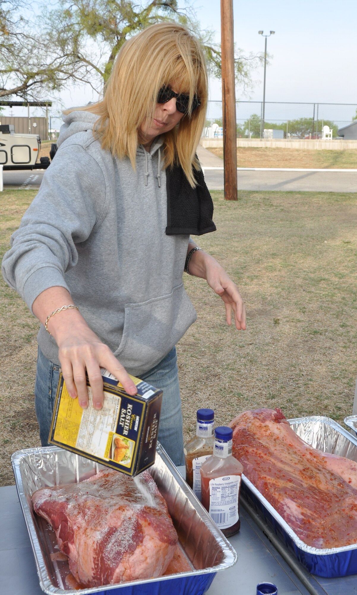 GOODFELLOW AIR FORCE BASE, Texas – Lori A. Keller, 17th Force Support Squadron Non-Appropriated Funds Accounting financial manager, pours salt on to a brisket during a cooking class at the Goodfellow Recreation Camp here April 19.  John M. Farris, rec. camp manager, taught the participants that salt helps make the meat tender.  (U.S. Air Force photo/ Senior Airman Joshua Edwards)