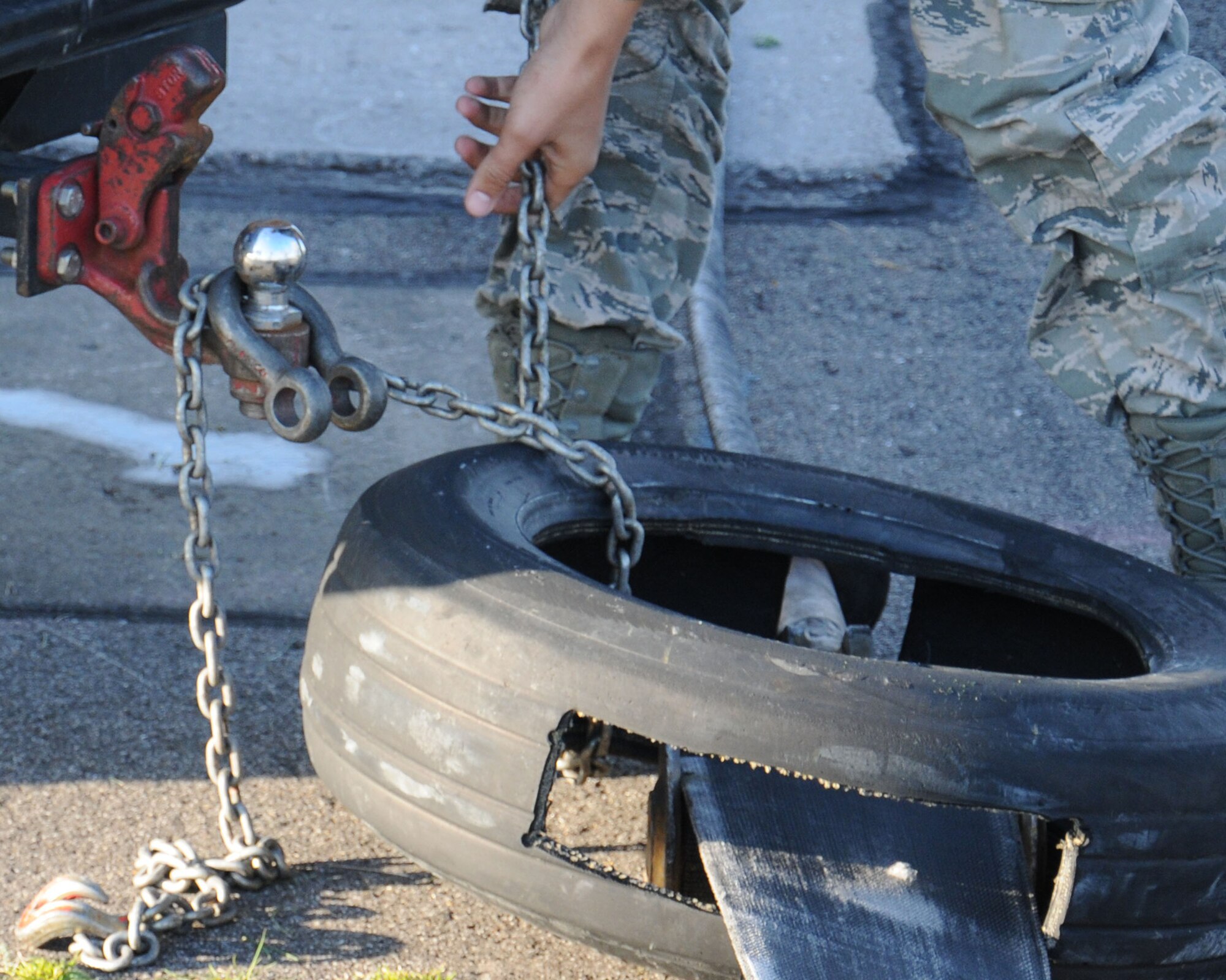 U.S. Air Force Staff Sgt. Bryan Anchondo, 100th Civil Engineer Squadron power production craftsman from Denver, hooks a runway barrier tape to a vehicle tow bar April 17, 2014, on RAF Mildenhall, England. The vehicle pulls the barrier tape to disconnect it from the pendant cable. After the removal, the vehicle tows the cable off the runway and deactivates it. (U.S. Air Force photo by Gina Randall/Released)