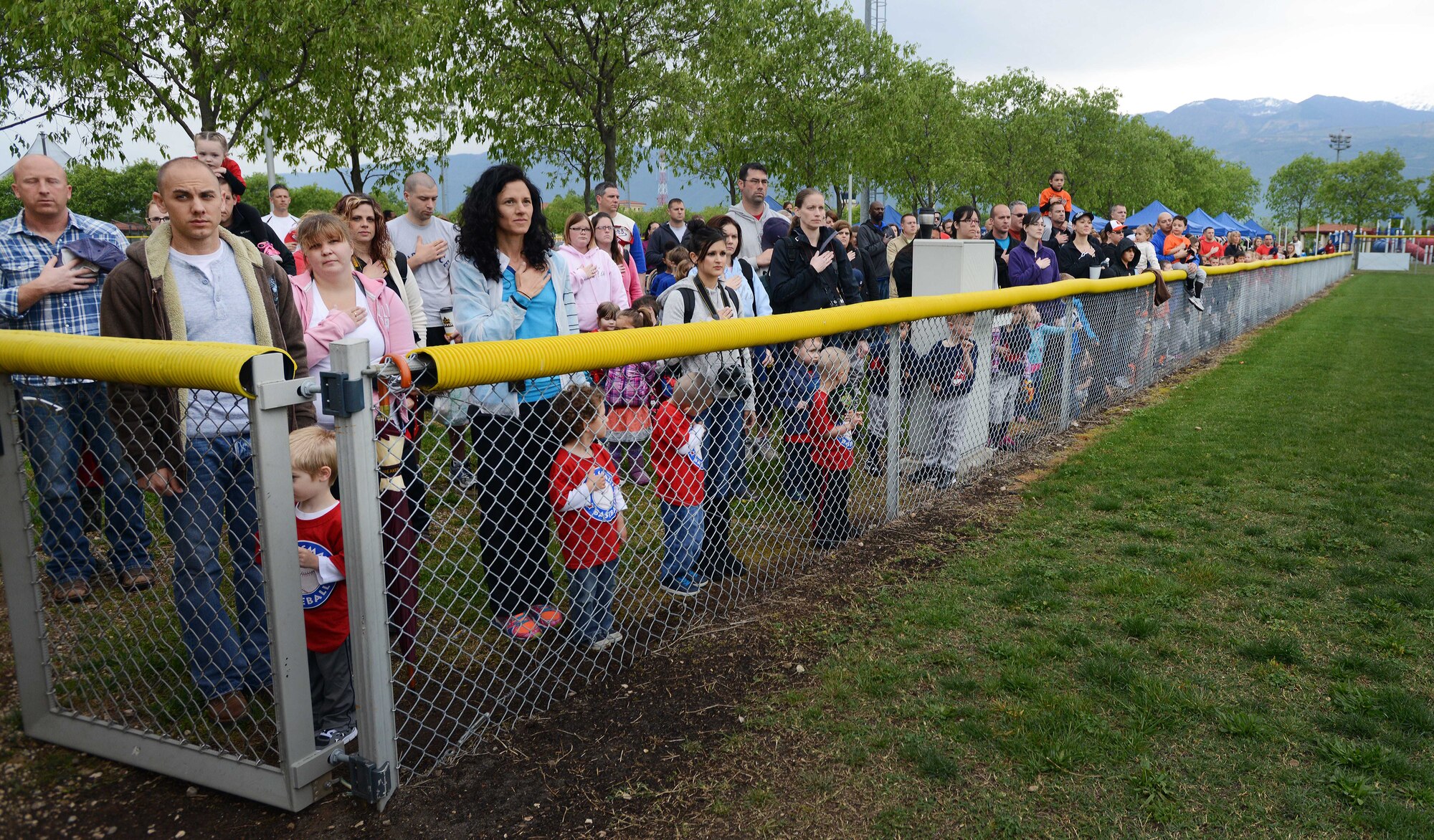 Parents and children place their hands over their heart during the singing of the National Anthem during the “Baseball Blast-off” event, April 19, 2014, at Aviano Air Base, Italy. The event kicked off the Aviano Youth Program summer sport season offered to children and teenagers between the ages of 3-18 years old. (U.S. Air Force photo/Airman 1st Class Deana Heitzman)  