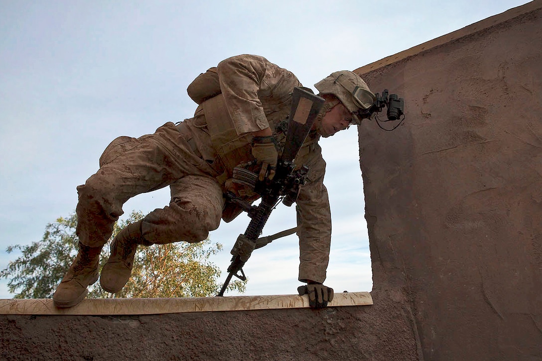 Marine Corps Lance Cpl. Michael Milano jumps over a wall during a mock helicopter raid as part of weapons and tactics instructor course Yuma Proving Ground, Ariz., April 9, 2014. Milano is an infantryman assigned to the 2nd Marine Division's India Company, 3rd Battalion, 6th Marine Regiment.