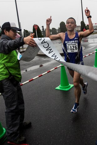 Nobuhisa Tanigawa, a participant of the 2014 Kintai Marathon, which took place aboard Marine Corps Air Station Iwakuni, Japan, runs through finish line tape after completing a marathon, April 13. The Kintai Marathon is one of the few annual events that give Japanese citizens an opportunity to come aboard station. Approximately 800 people signed up for the full marathon, half marathon and five-kilometer walk.