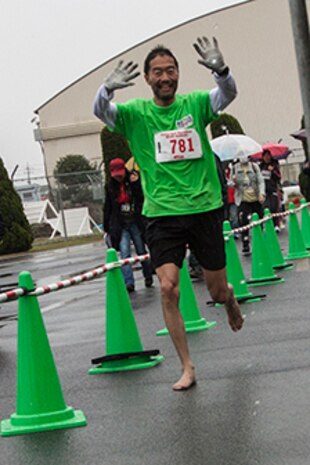 A Japanese participant of the 2014 Kintai Marathon, which took place aboard Marine Corps Air Station Iwakuni, Japan, runs barefoot toward the half-marathon finish line, April 13. The Kintai Marathon is one of the few annual events that give Japanese citizens an opportunity to come aboard station. Approximately 800 people signed up for the full marathon, half marathon and five-kilometer walk.