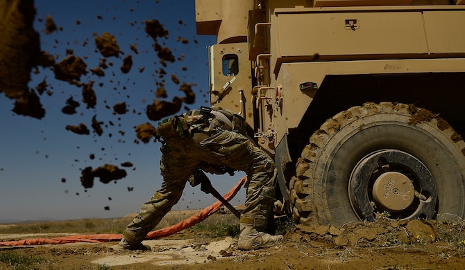 Staff Sgt. Kyle McGann digs mud from under a mine resistant ambush protected, or MRAP, vehicle March 16, 2014, during demolition day at Kandahar Air Field, Afghanistan. McGann is a 466th Air Expeditionary Squadron, explosive ordnance disposal technician. (U.S. Air Force photo/Staff Sgt. Vernon Young Jr.) 
