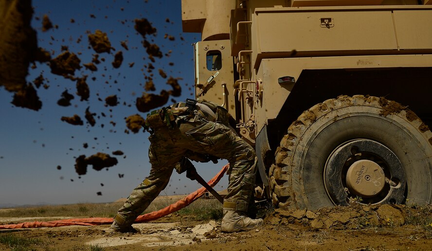 Staff Sgt. Kyle McGann digs mud from under a mine resistant ambush protected, or MRAP, vehicle March 16, 2014, during demolition day at Kandahar Air Field, Afghanistan. McGann is a 466th Air Expeditionary Squadron, explosive ordnance disposal technician. (U.S. Air Force photo/Staff Sgt. Vernon Young Jr.) 
