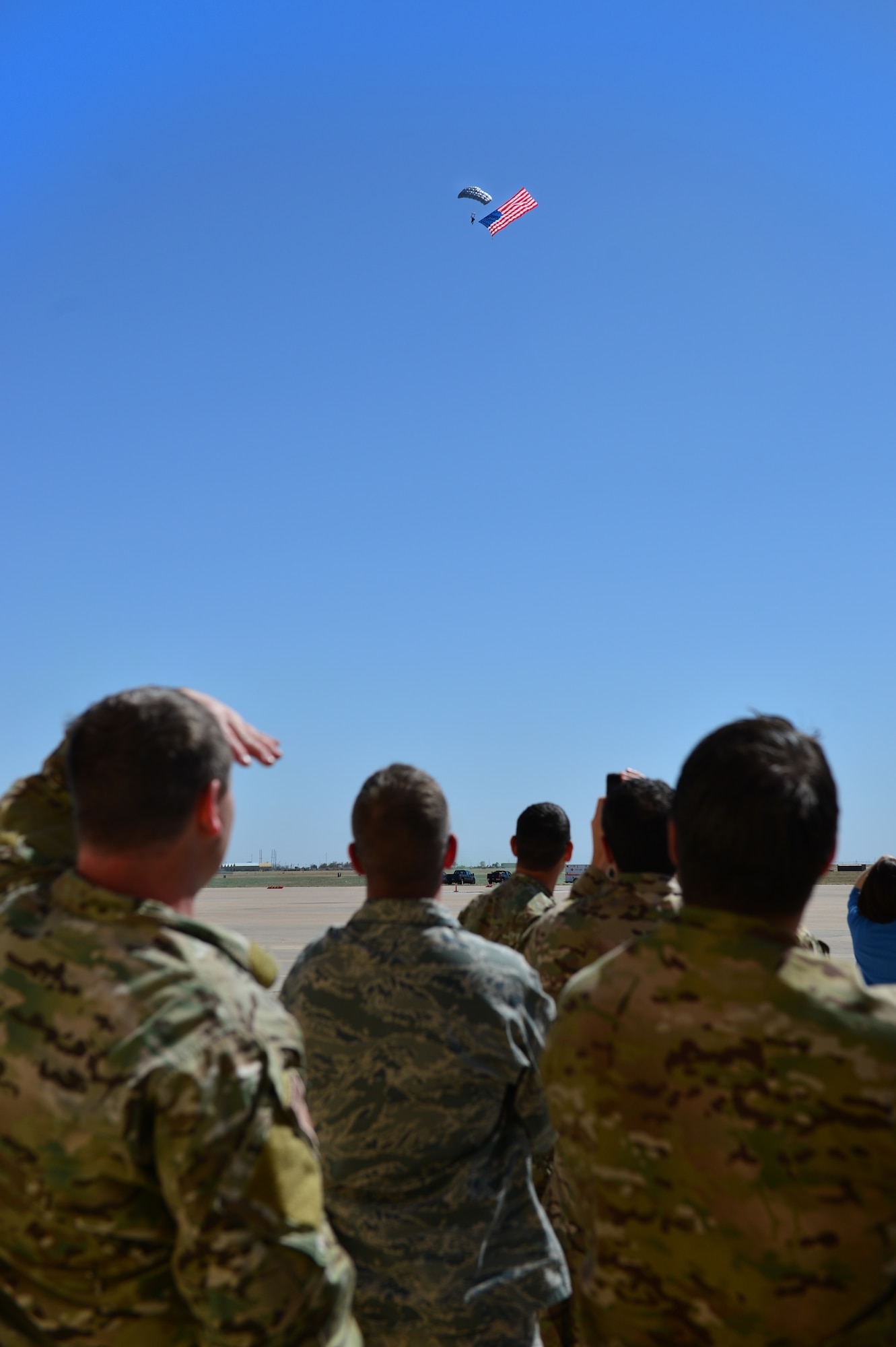 Viewers watch as a member of the 26th Special Tactics Squadron parachutes onto the flightline with an American flag, April 24, 2014 at Cannon Air Force Base, N.M. The 26 STS, formerly Detachment 1 of the 720th Special Tactics Group, Hurlburt Field, Fla., is a newly activated squadron based at Cannon. (U.S. Air Force photo/ Senior Airman Eboni Reece)