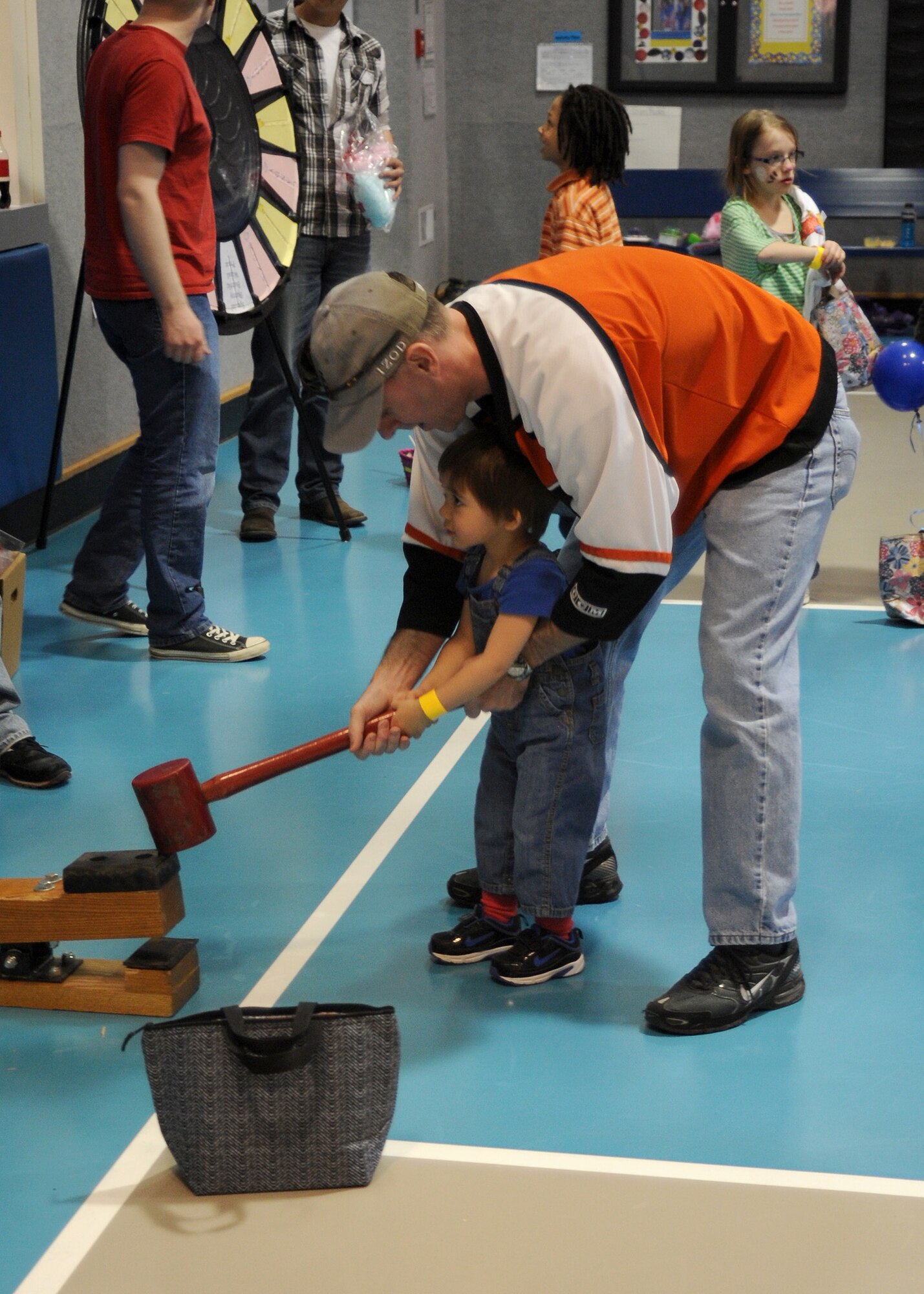 Lt. Col. Chad McAdams, 341st Comptroller Squadron commander, helps his son, David, use a hammer for a game at the Youth Programs Spring Carnival. Children were able to win candy and small toys for partaking in games at the carnival. (U.S. Air Force photo/Senior Airman Cortney Paxton)