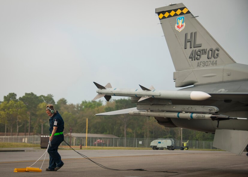 Tech Sgt. Allison Tolar, 419th Aircraft Maintenance Squadron crew chief, hauls the tire-stoppers from the wheels of an F-16's landing gear. The F-16 flew with the F-35  today as part of immersion training at Eglin Air Force Base, Fla. (U.S. Air Force photo/Senior Airman Crystal Charriere)
