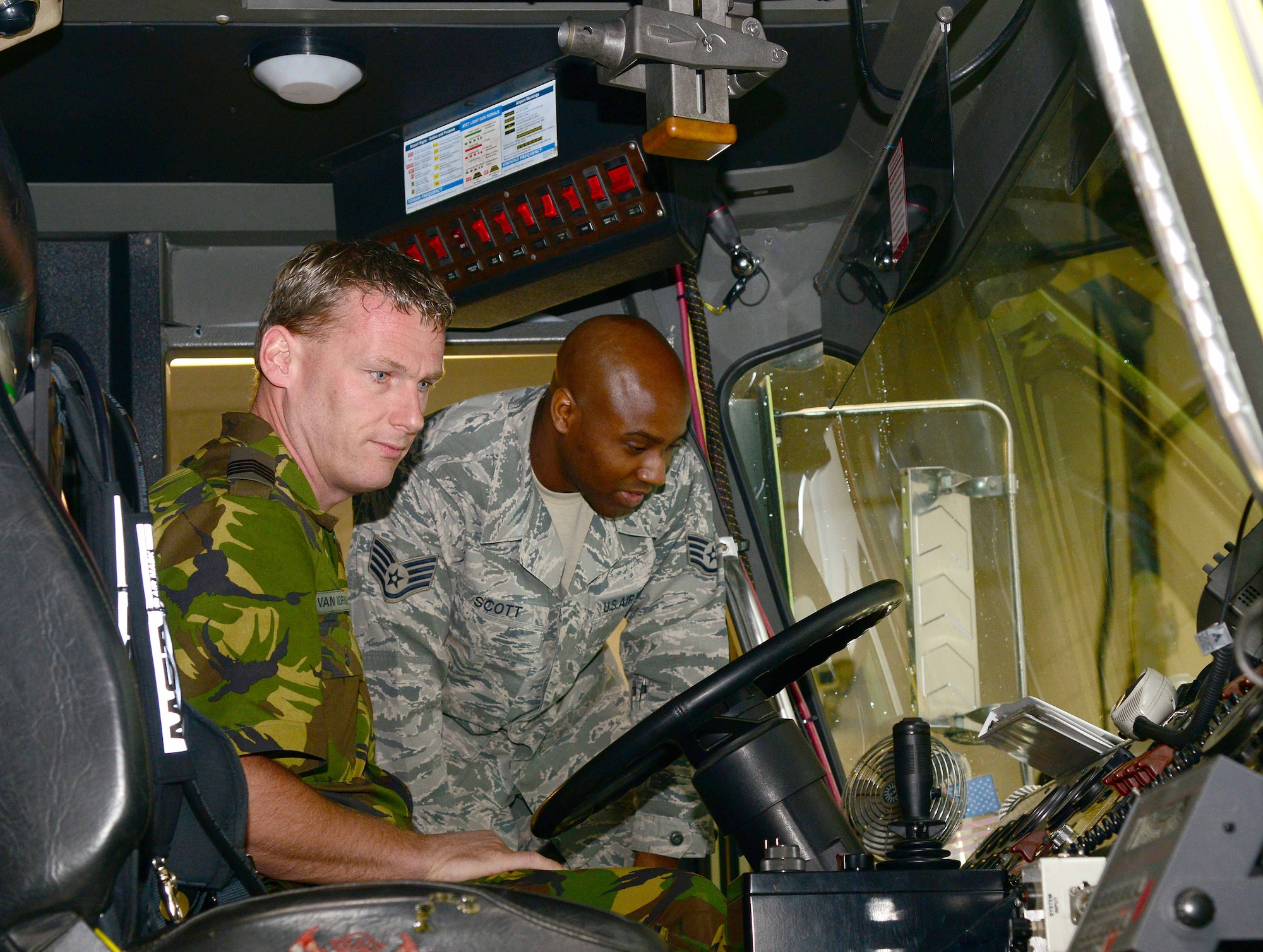 U.S. Air Force Staff Sgt. Dennis Scott, 633rd Civil Engineer Squadron Fire Department crew chief, shows engine functions to Royal Netherlands Air Force Sgt. Maj. Rene Van Noordeme, firefighter and on scene commander at Langley Air Force Base, Va., April 23, 2014. Noordeme toured the 633rd Fire Department facility, studied vehicle features and watched Airmen don fire protective gear. (U.S. Air Force photo by Staff Sgt. Antoinette Gibson/Released)